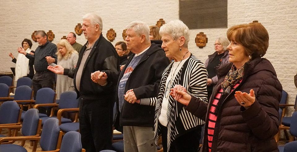 Retreatants at Mass in the Chapel at Capuchin Retreat. They are holding hands and praying the "Our Father."