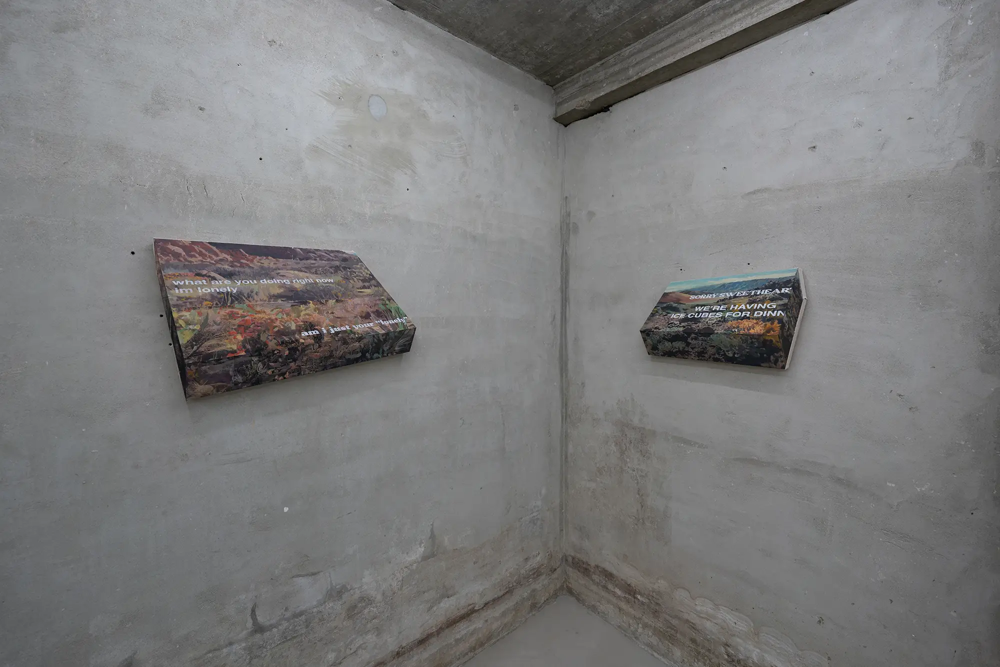 installation view of michael rikio ming hee ho's exhibit at sangheeut gallery with two text-based mixed media artworks on a concrete wall