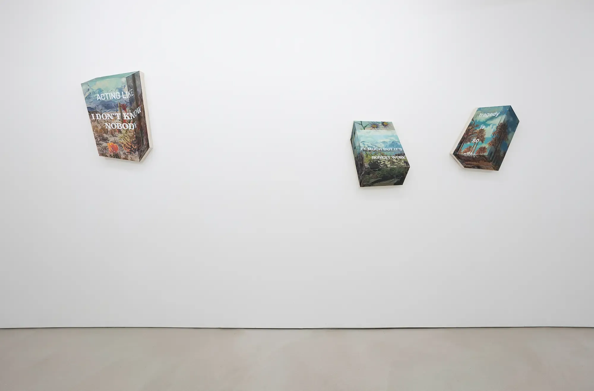 installation view of michael rikio ming hee ho's exhibit at sangheeut gallery with three text-based mixed media artworks on a white wall