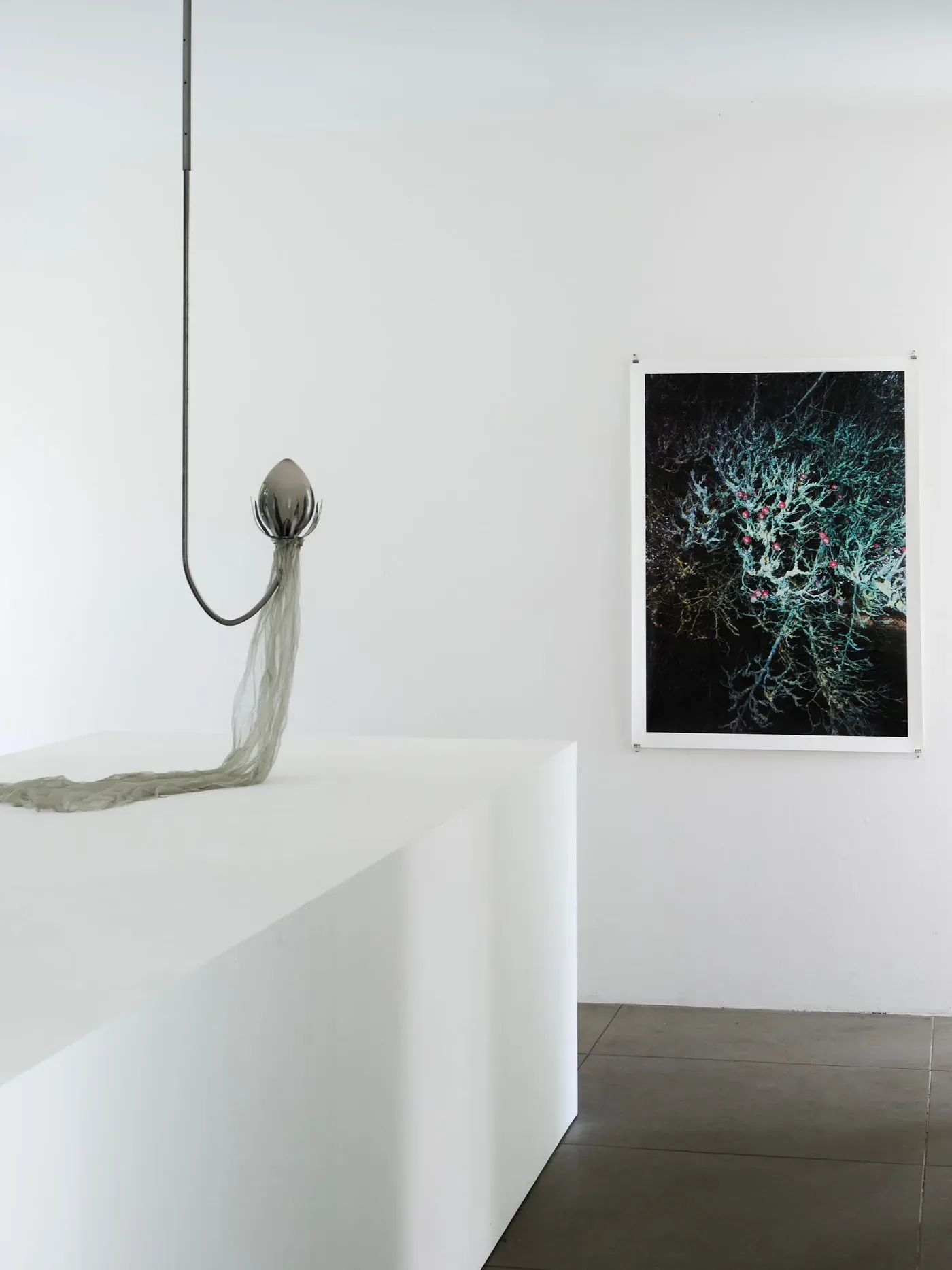 Futuristic hanging sculpture with metallic form and printed image on wall, installation view at Wehrmühle Biesenthal, Some Degree of Friction 2025.