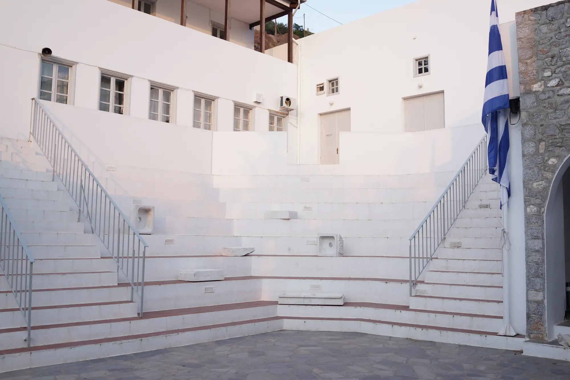 Courtyard of Hydra School Projects 2025 on Hydra Island, Greece, showing marble fountain sculptures by Dimitrios Antonitsis installed on the amphitheatre steps for the exhibition Lithos Lethe.