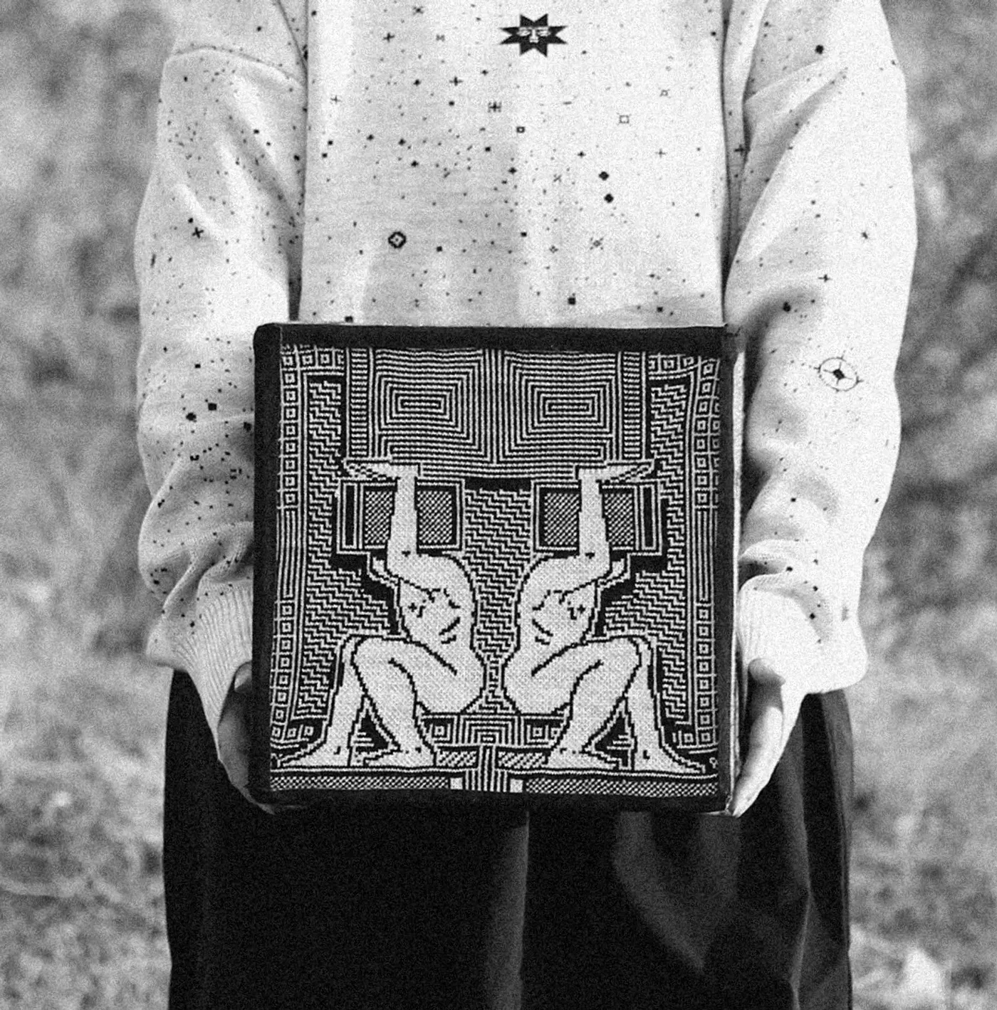 Matevosyan woven cube with mirrored human figures, geometric motifs, Armenian folklore, and digital-inspired textile design, held in hands.