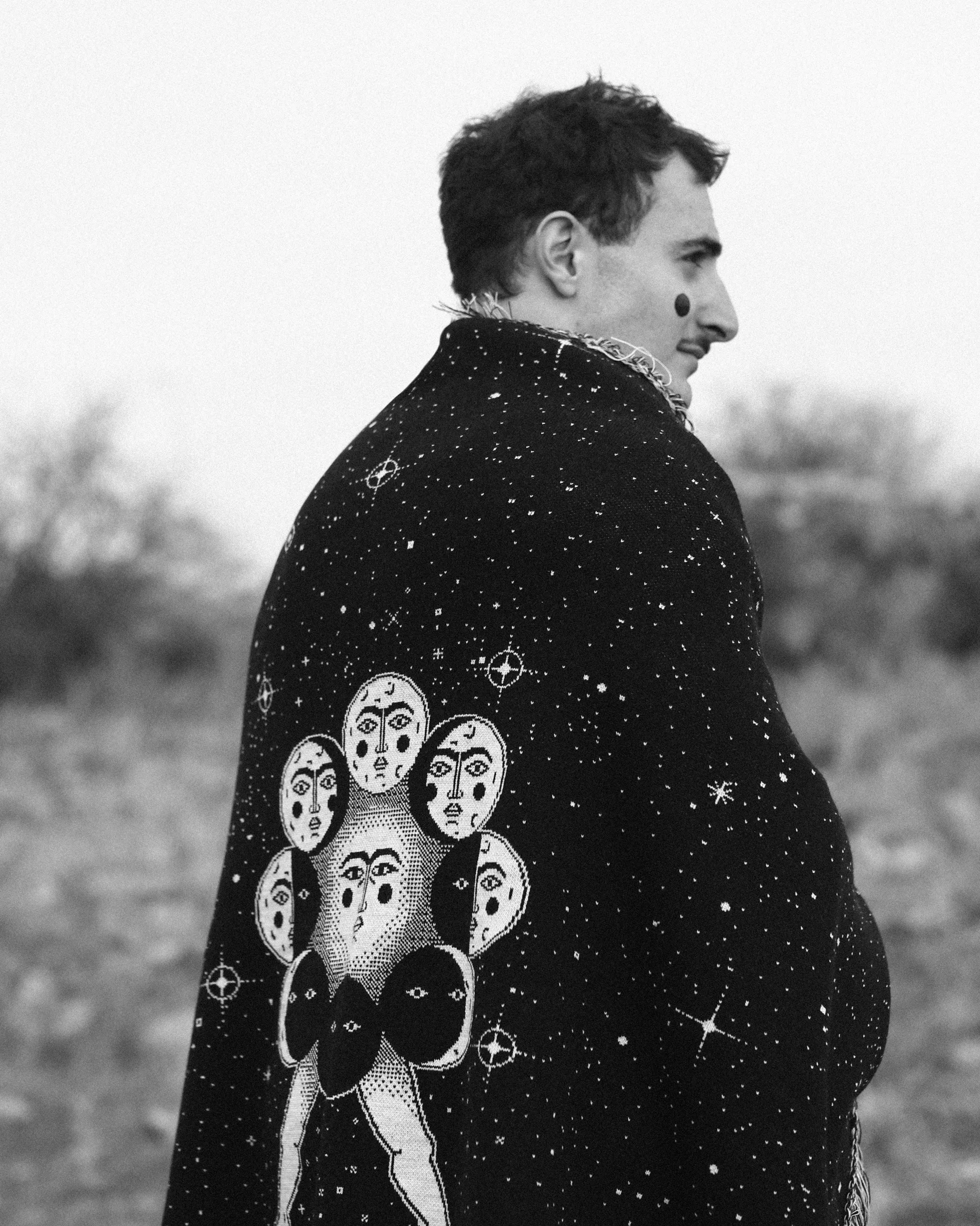 Matevosyan EMERGENCE: Space and Adventure woven cloak with cosmic star field and multi-faced figures, merging Armenian folklore with digital-inspired textile design. 
