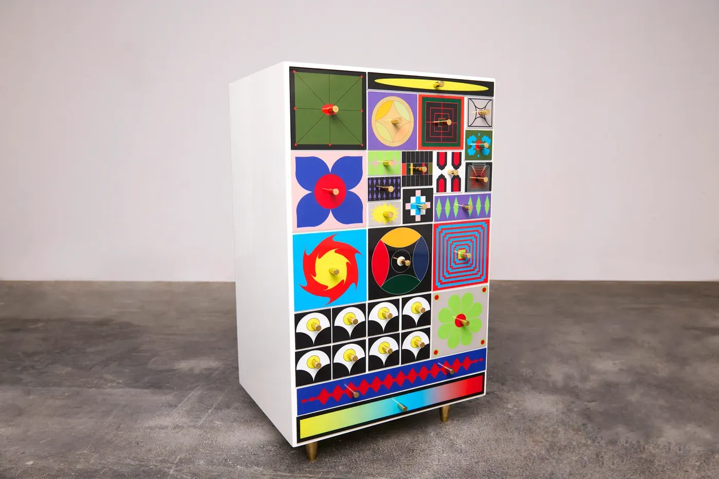 Kumkum Fernando – Angled view of the 27th Century Collector’s Cabinet, featuring colorful geometric patterns, lacquered finish, and brass details, merging functional furniture with futuristic mythology. 