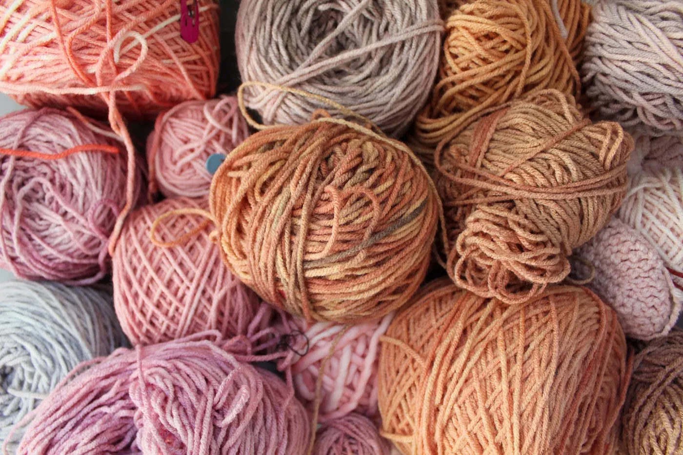 Ophelia Arc studio materials showing balls of hand-dyed yarn in pink, brown, and flesh-like tones