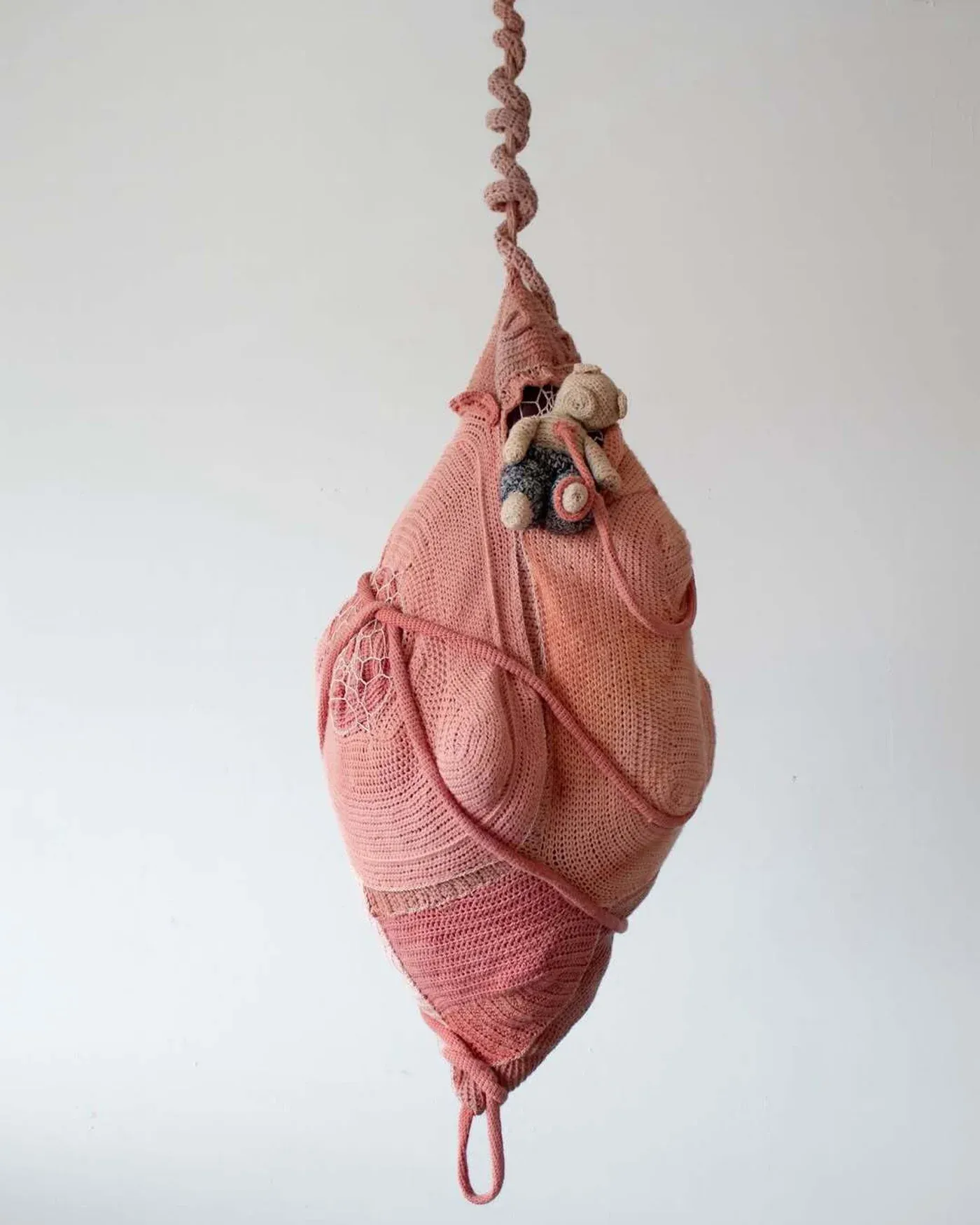 Ophelia Arc textile cocoon sculpture in pink yarn with small toy bear attached, from thesis exhibition