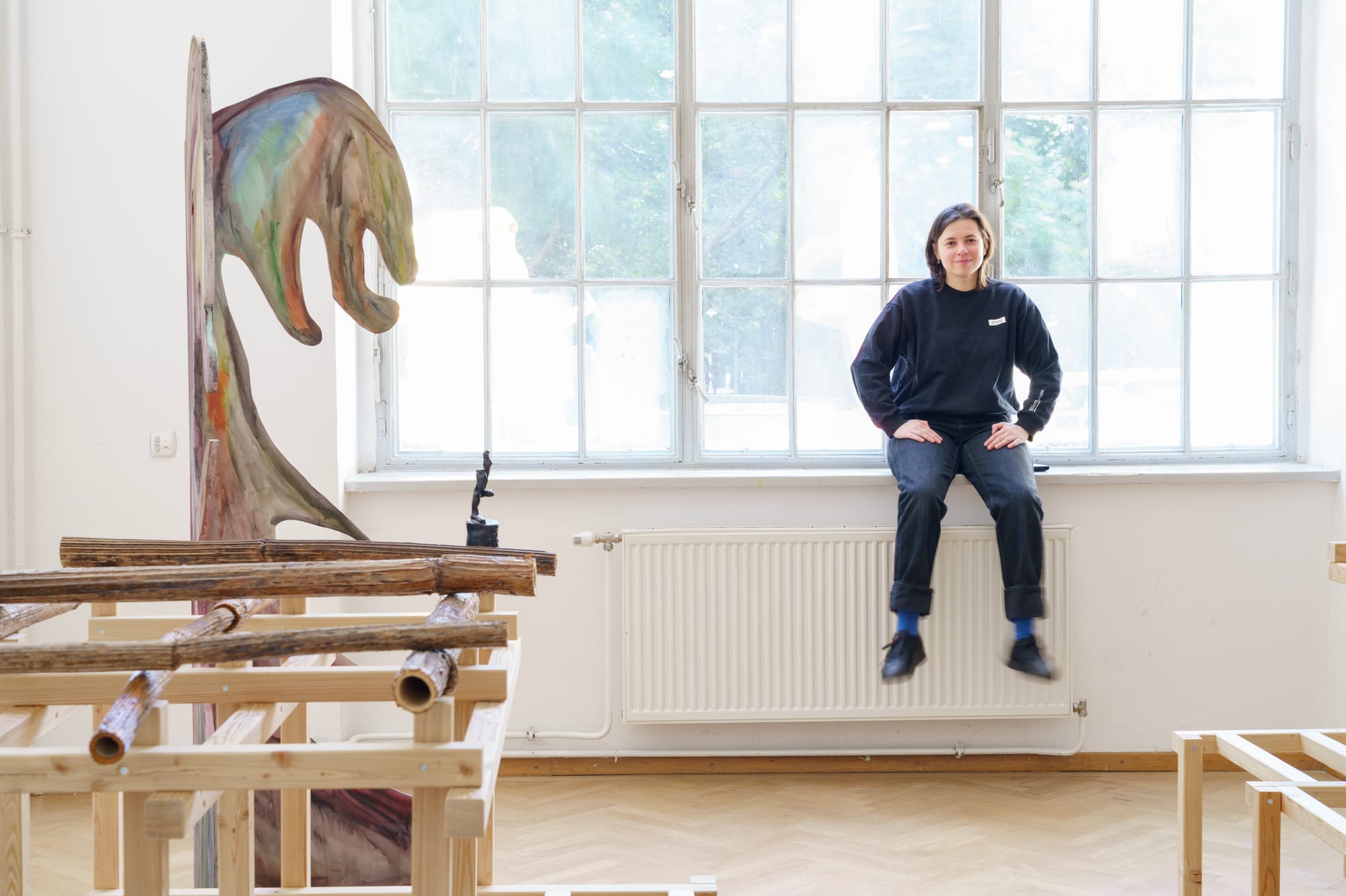Parallel Vienna 2025 Artist Statements – Natalia Gurova presents diploma sculptures from the Academy of Fine Arts Vienna, seated in studio with wooden installation. Photo by Olga Shapovalova.