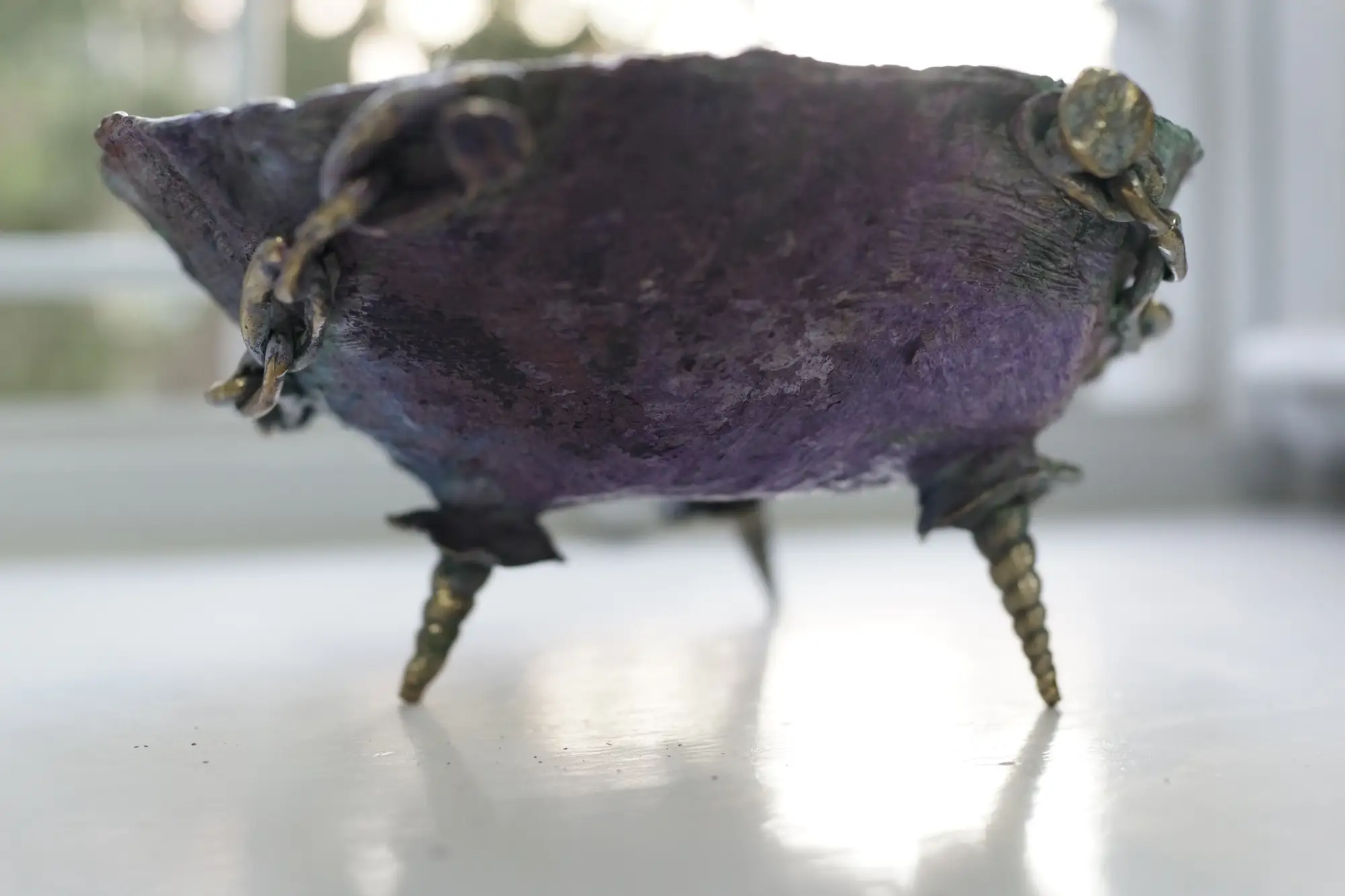 screw-like legs with a textured purple surface, combining artifact-like solidity with surreal design.