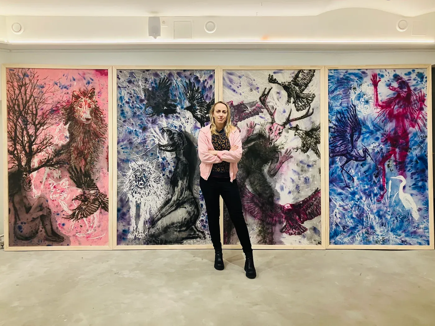 olga pastekova stadın infront of 3 of her artworks