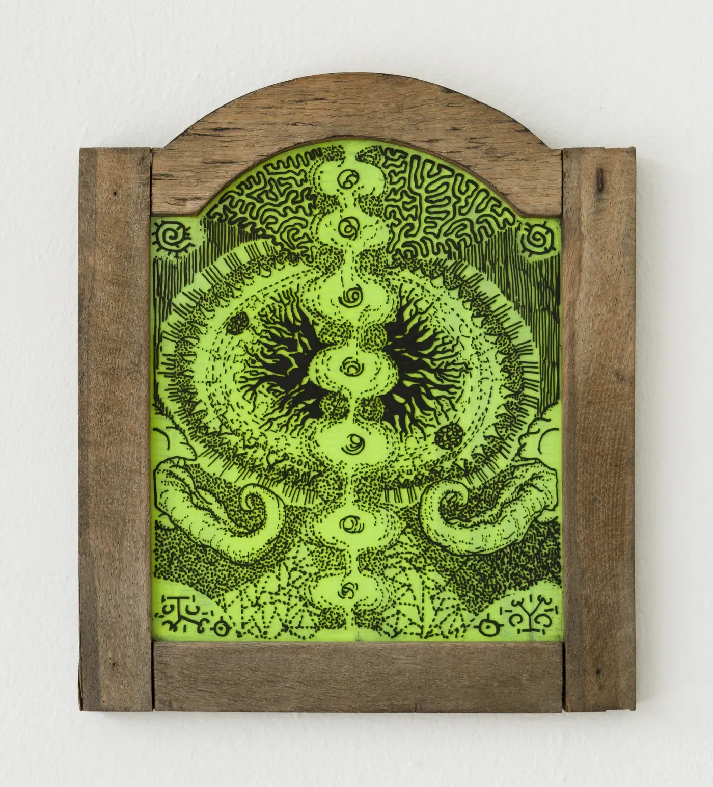Stefan Bakmand: “A Thick Trip,” neon green organism icon in rustic wooden frame, Bybliomoebick Mouseion, 2025. Photo Luna Lund Jensen. Image courtesy the artist.