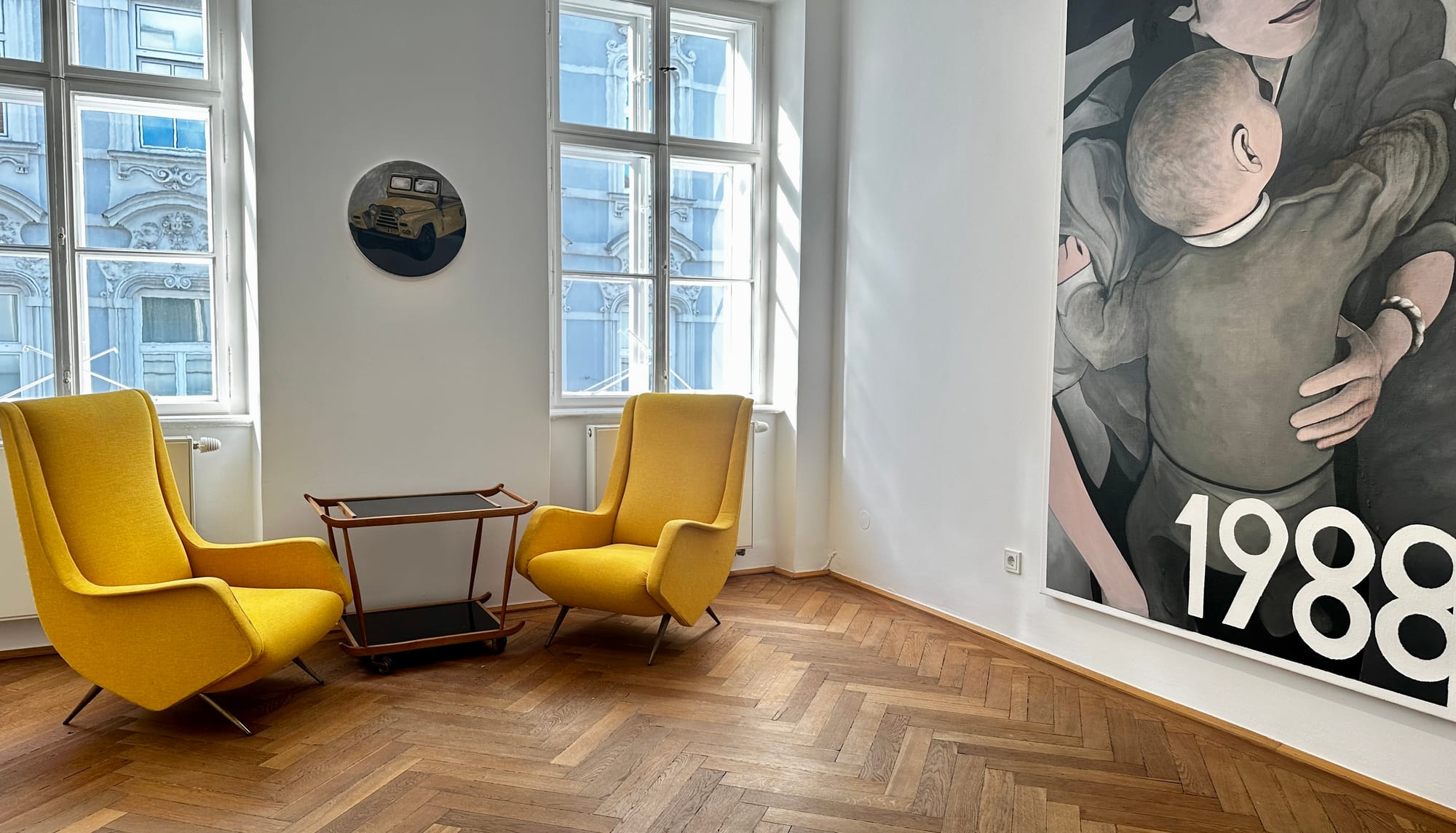 Christiof Habres and Alexander Giese curated and discover (Klubhaus, Kunst und Schnittlauch. Artist Talk with, Tin Trohar: Seating area at Klubhaus with a round Jeep painting on the wall and the edge of the mother-and-child painting from “1996.