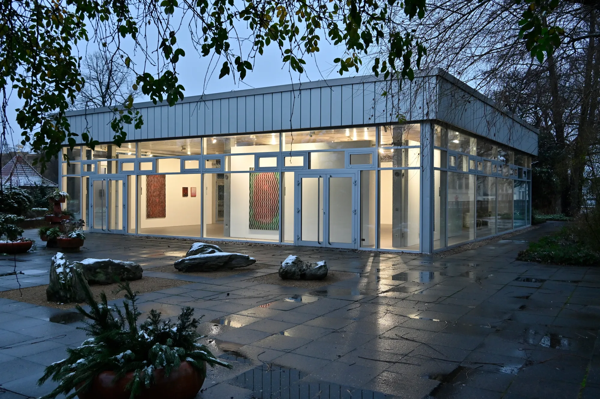 Matthias Esch, Deranged Chanting exhibition view II, 2024, exterior evening view of Kunstverein gallery with illuminated abstract paintings visible inside, photo by Michael Lüder.