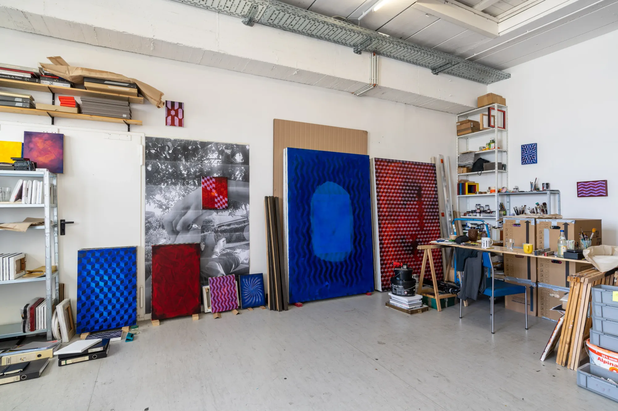 Matthias Esch: Studio View.  Artists studio, very clean and tidy, with red and blue abstract paintings by the artist 