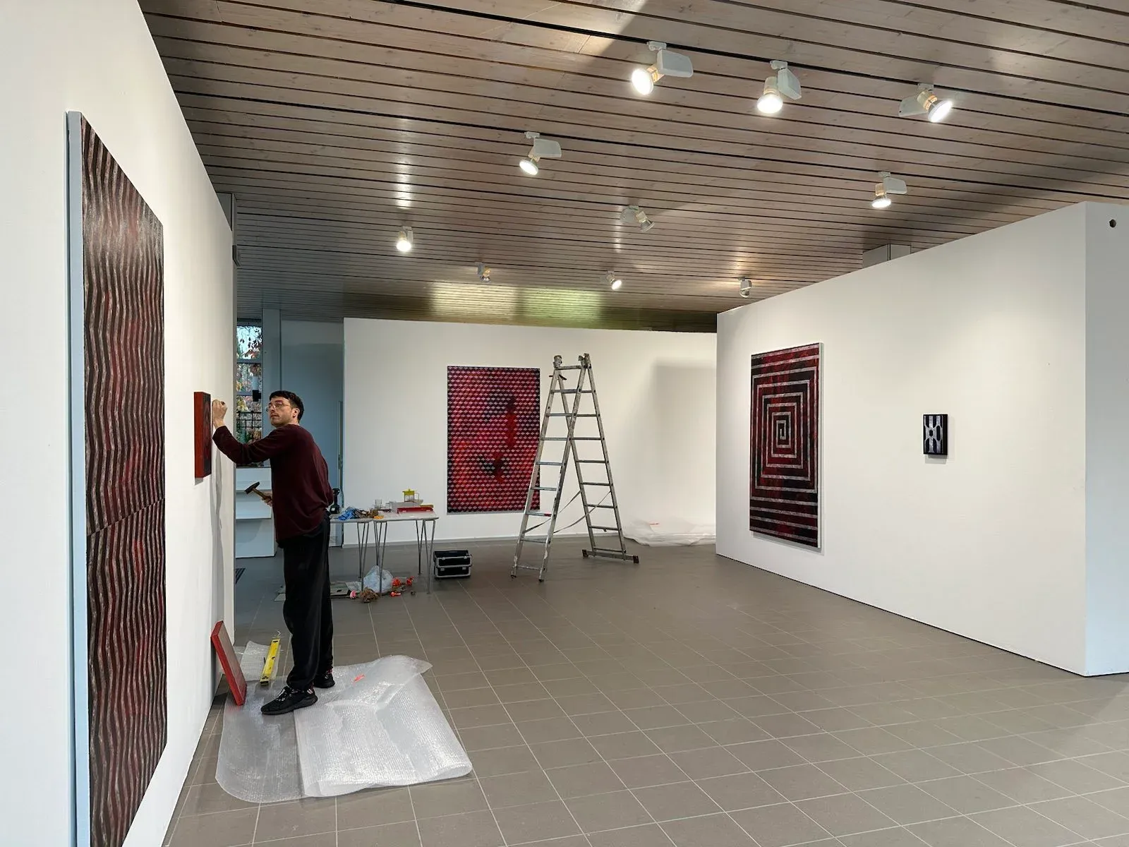 Matthias Esch, Deranged Chanting installation setup, artist preparing abstract geometric paintings in exhibition space, 2024.