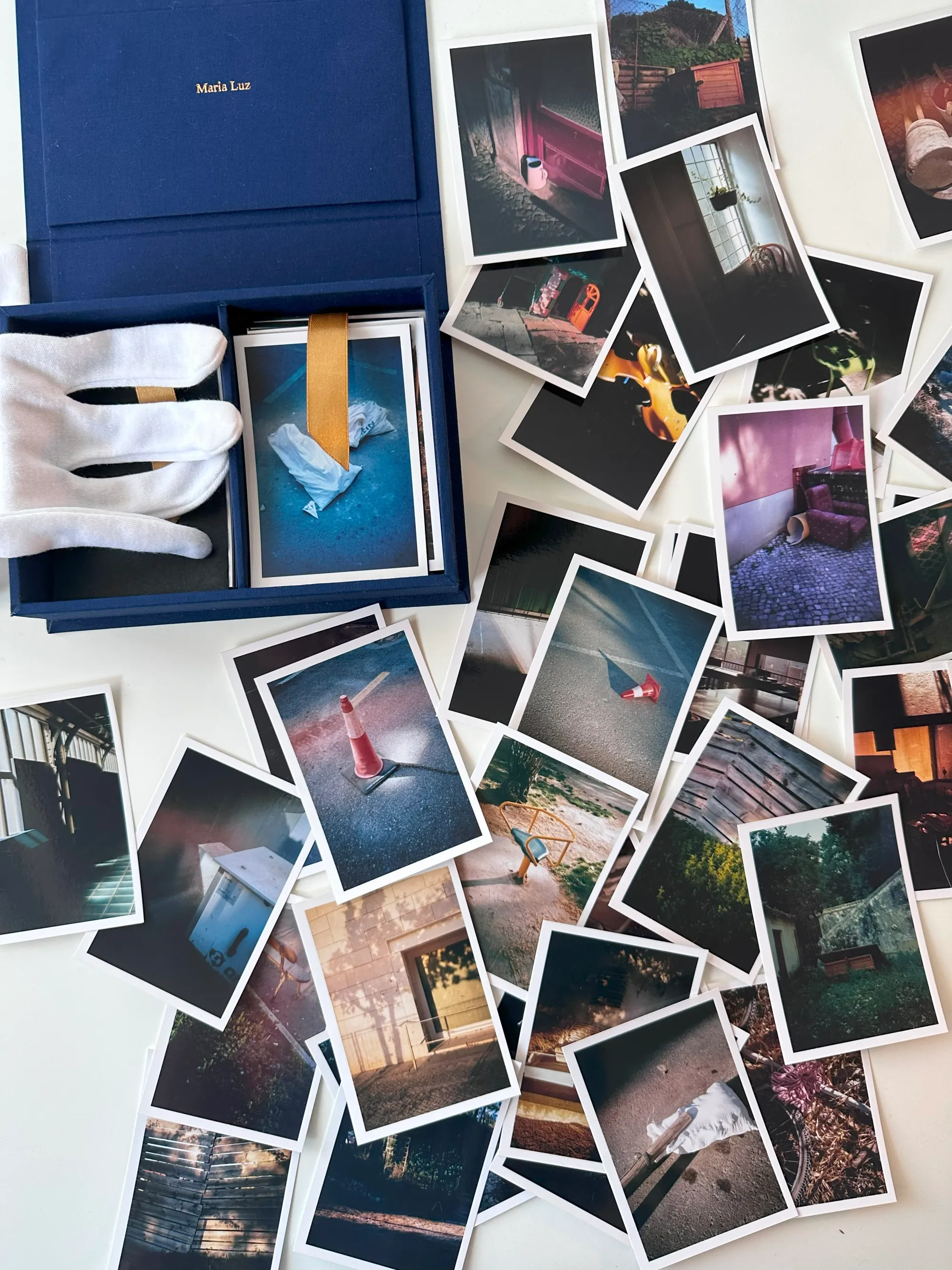 Maria Luz, studio table view with open photo box and scattered film prints, Lisbon studio.