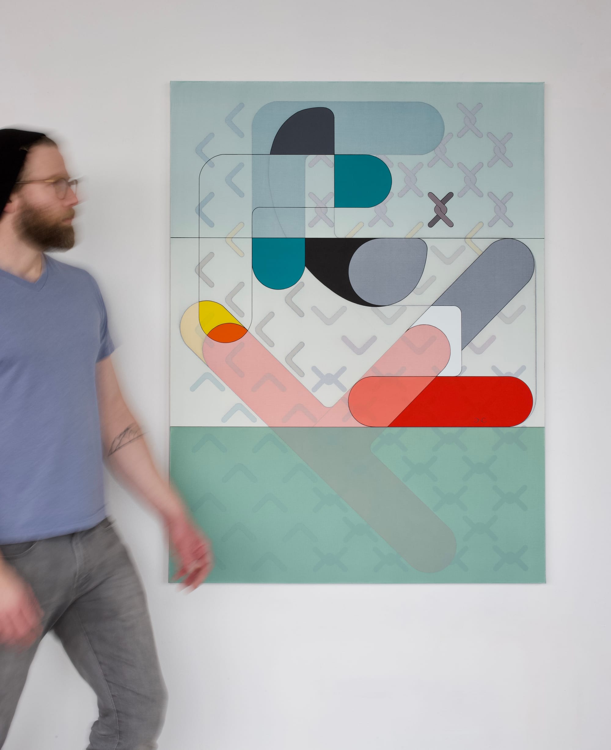 Chris Cassimatis walking past his painting ‘Entanglement Theory’ in Chicago, showing abstract geometric forms in soft tones and bold accents. Image Courtesy of the Artist