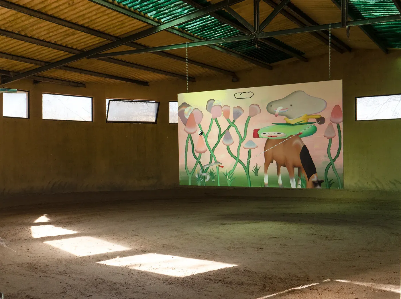 Large mixed media painting by Grip Face hanging in an empty stable. The artwork shows surreal figures, pastel colors, and a horse with stylized plants. Site specific work created during the EL Núcleo Foundation residency in Segovia