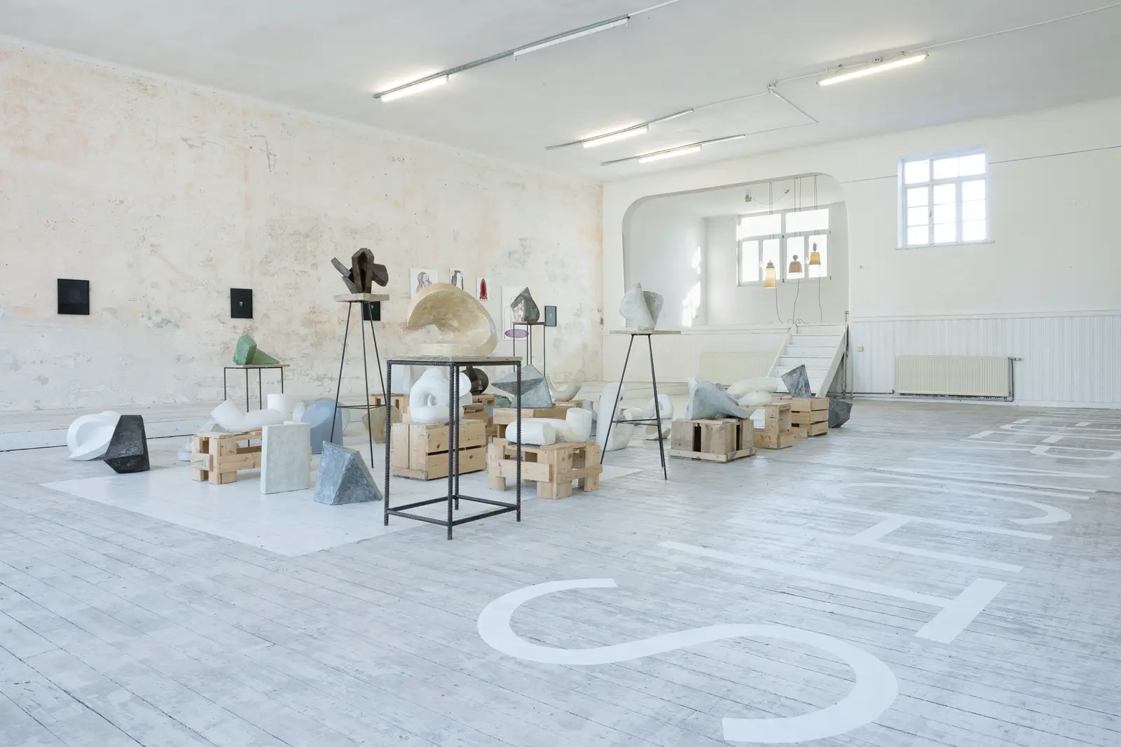 Exhibition view of Kunstverein Schattendorf showing sculptural works arranged on crates and metal stands in a bright white room.