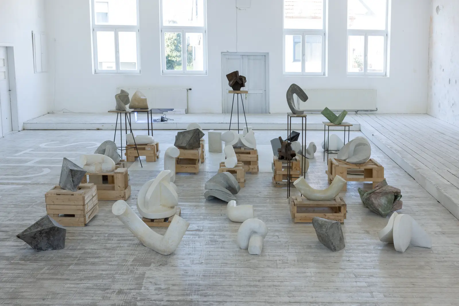 Installation by Rouven Dürr at Kunstverein Schattendorf showing plaster, concrete and steel sculptures arranged on wooden crates in a bright white exhibition space.