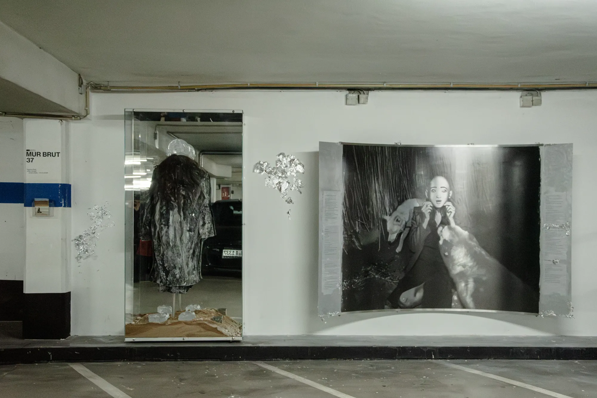 Installation view of After Unrast by Nadine Karl at Kunsthalle Düsseldorf, showing a glass display with sculptural elements and a large black-and-white photographic work mounted on the wall.