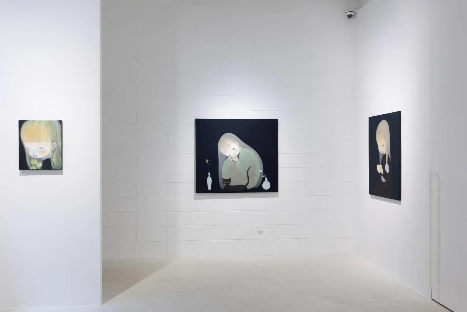 Installation view of three paintings by Ruo-Hsin Wu displayed across white gallery walls at Eligere Gallery, featuring pale figurative figures set against dark backgrounds.