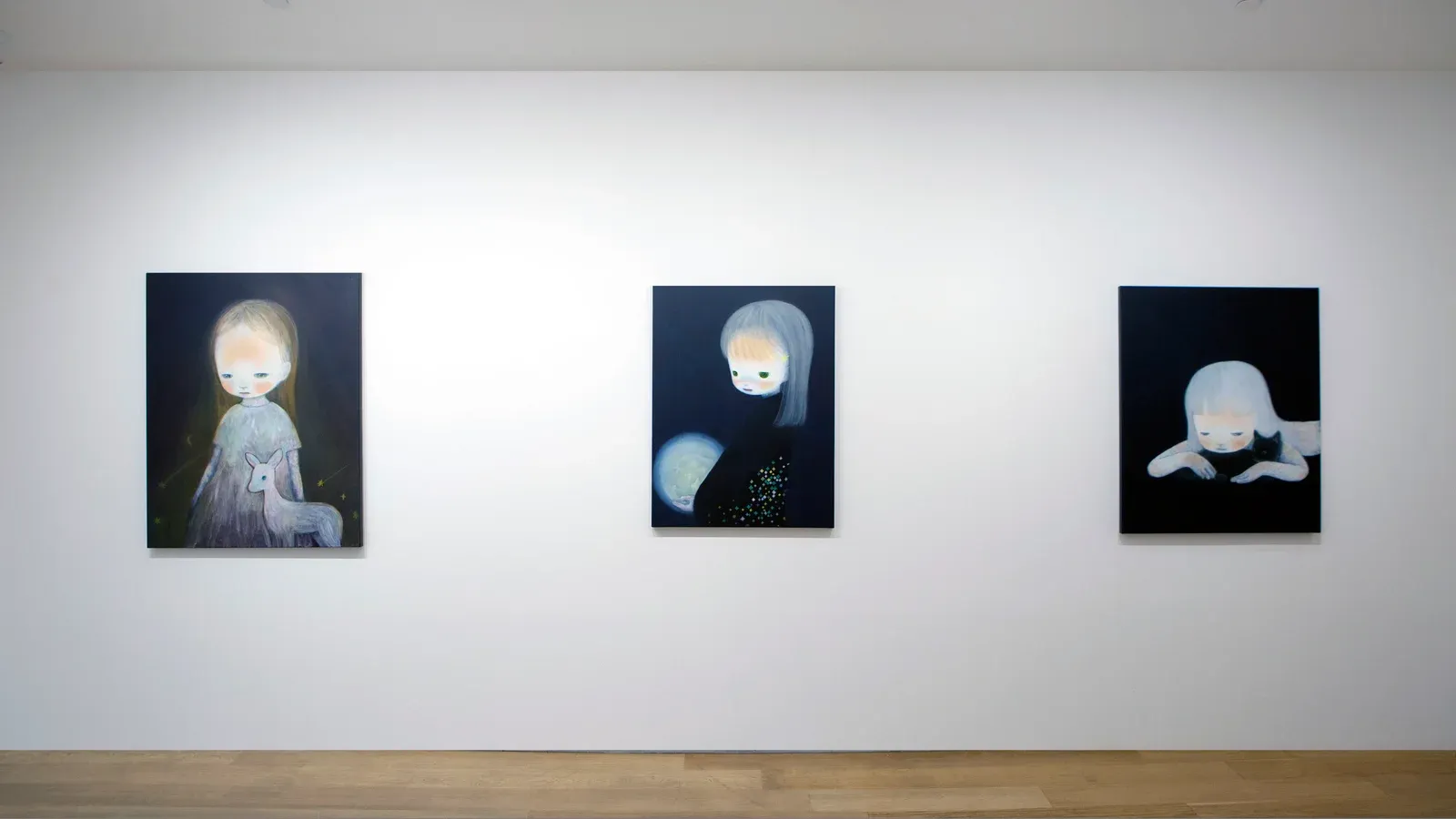 Installation view of three paintings by Ruo-Hsin Wu displayed on a white gallery wall at Tang Contemporary Art, featuring pale figurative figures set against dark backgrounds.