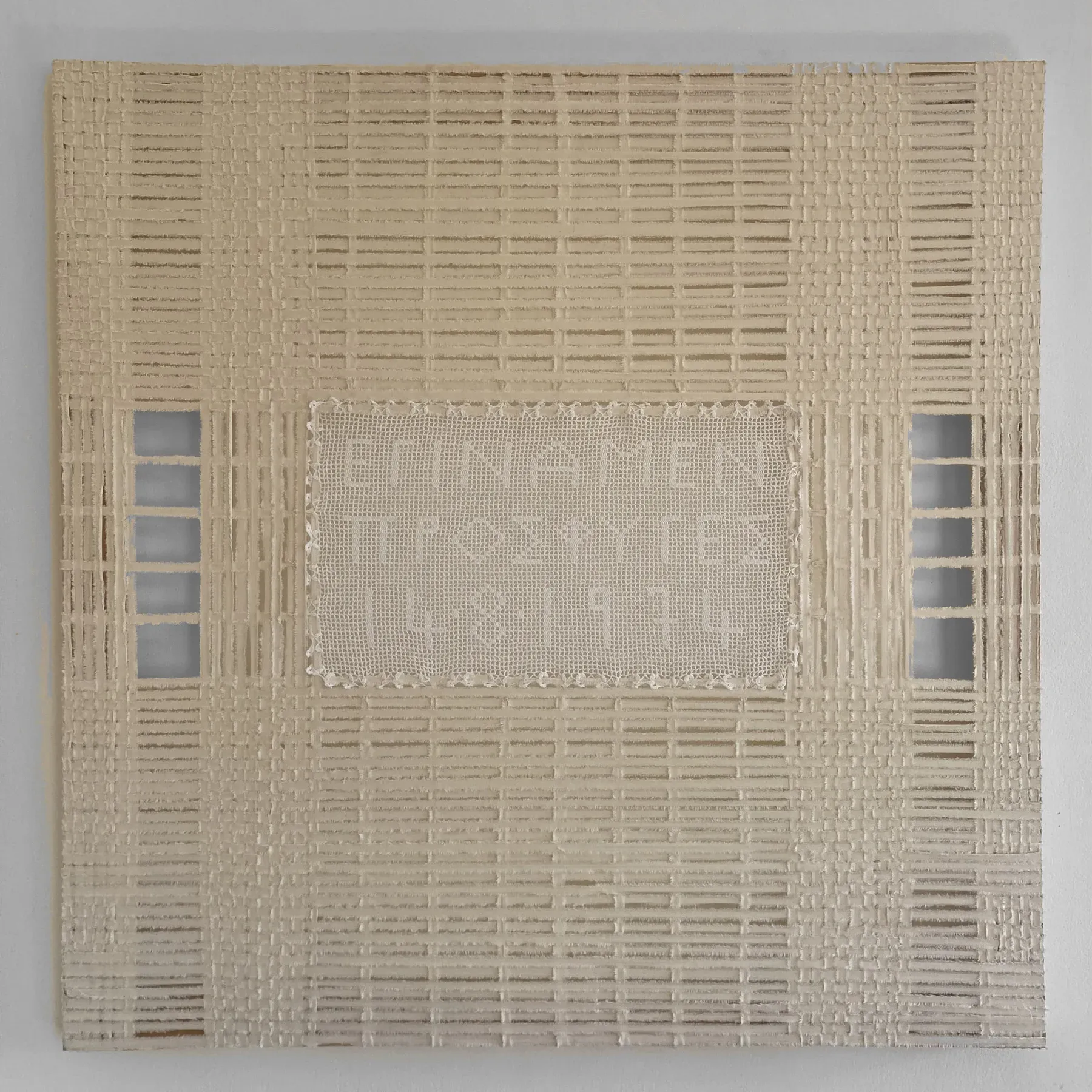 A square textile work composed of woven canvas and found materials, featuring a central stitched panel with text integrated into a grid-like fabric structure.
