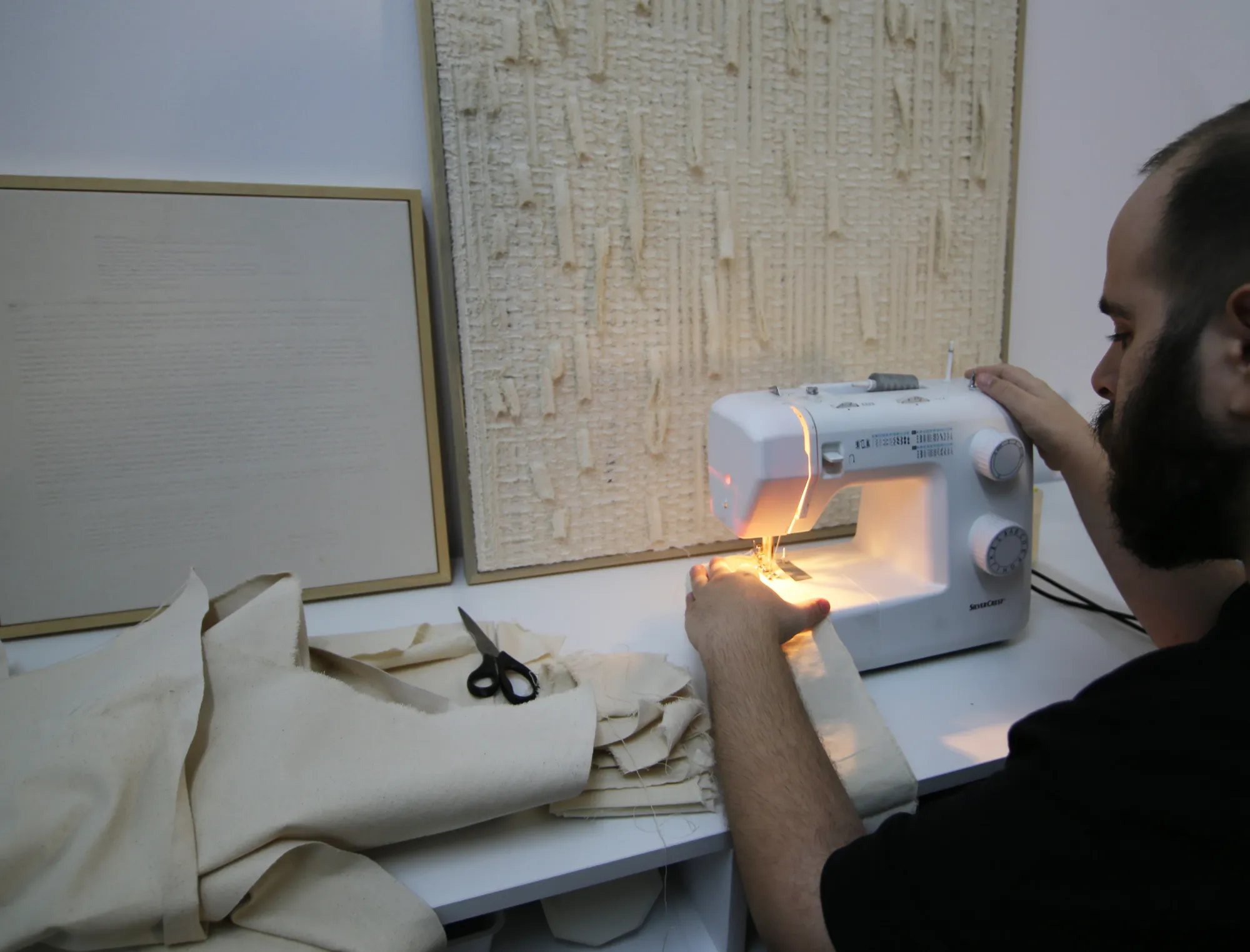 Avraam Hirodontis sewing layered fabric on a domestic sewing machine, focusing on precision, rhythm, and material tension.