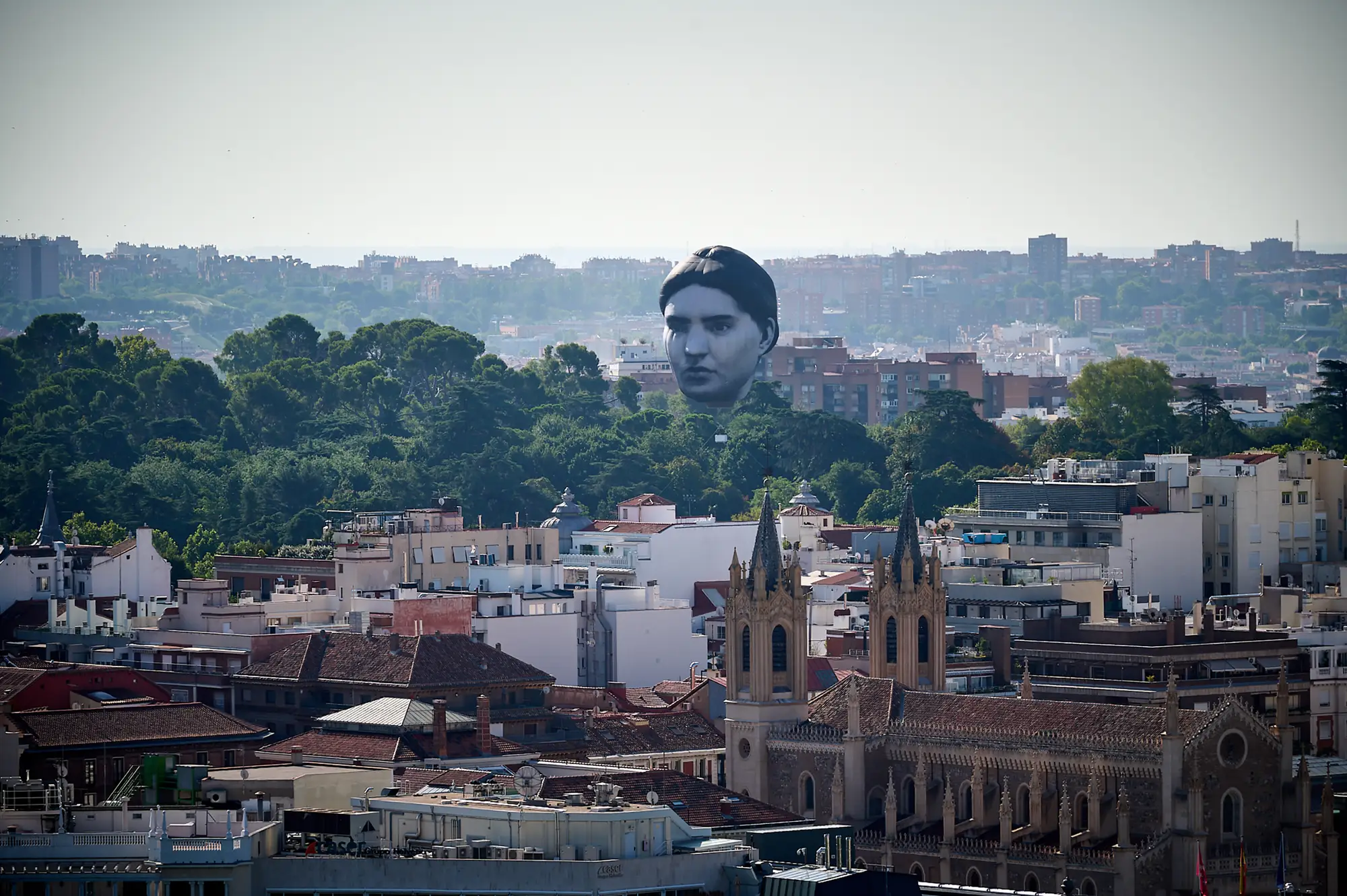 目 [mé] art collective,  masayume (2024) monumental floating head sculpture rising above the skyline of Madrid during Veranos de la Villa 2024, presented by The Japan Foundation.
