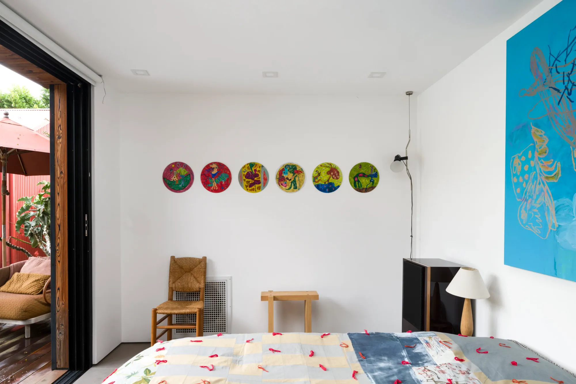 Installation view of Dinner Table at Simchowitz Hilltop, Los Angeles, featuring circular paintings by Lera Derkach and a large painting by Andrey Samarin within a staged bedroom interior.