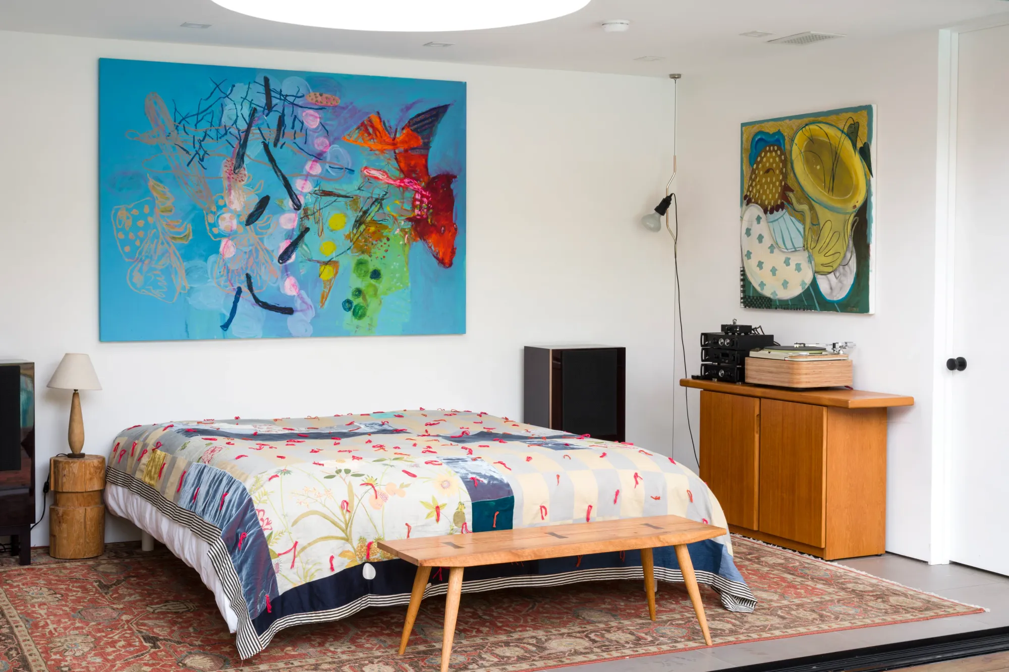 Installation view of Dinner Table at Simchowitz showing paintings by Andrey Samarin and Lera Derkach installed above a bed within a staged domestic interior.