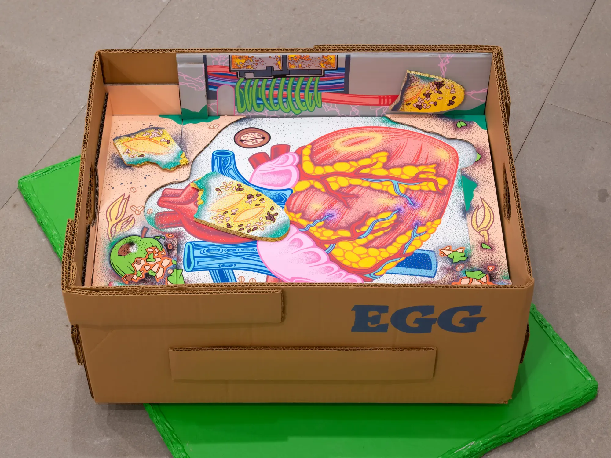 Cardboard box labeled EGG containing colorful painted anatomical heart and food fragments, symbolic sculpture by Daniela Ponomarevová