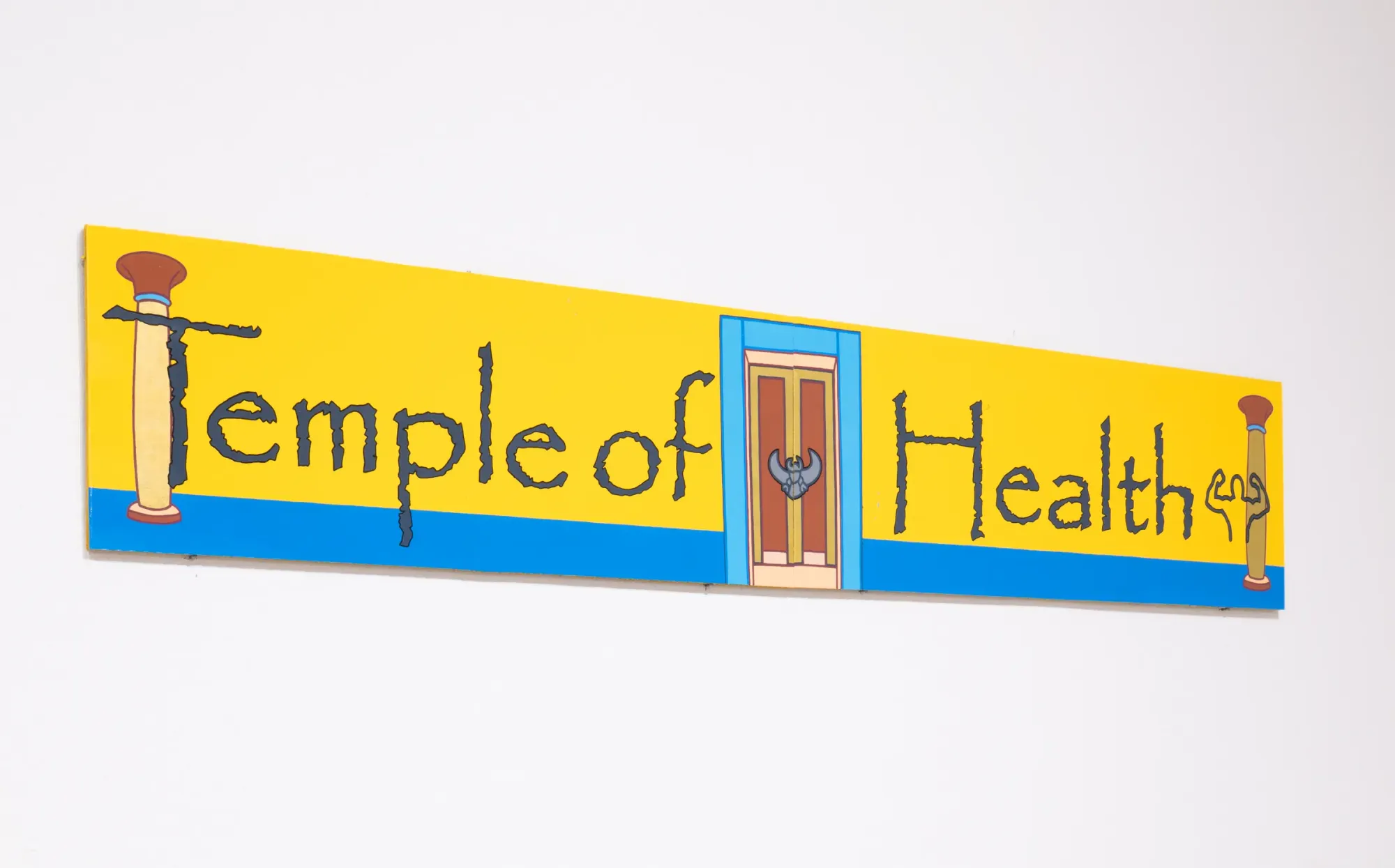 Bright yellow Temple of Health sign with illustrated door and symbols, hand-painted cardboard work by Daniela Ponomarevová