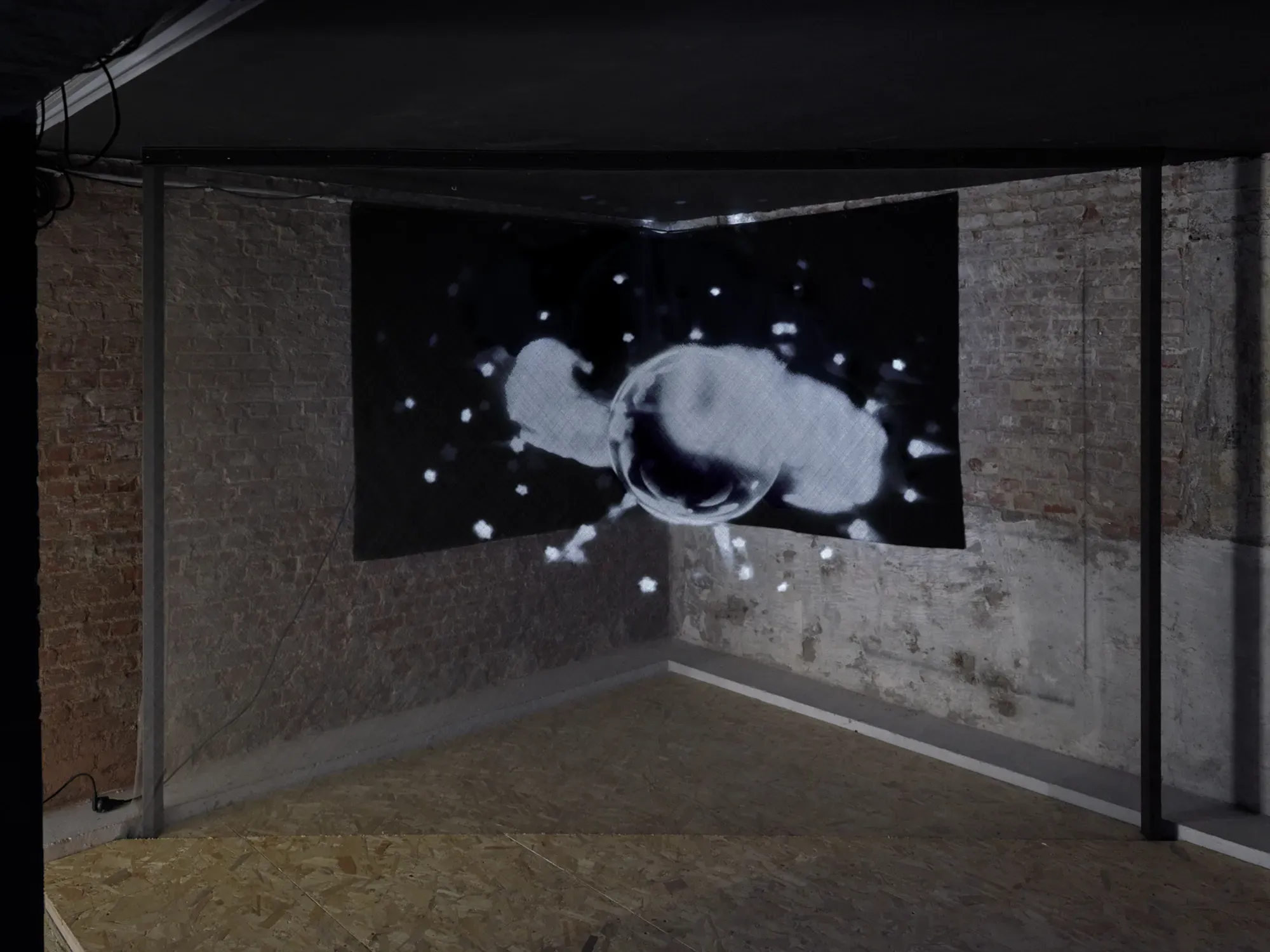 Video still from Banks Violette’s Untitled (Universal Pictures), 2026, showing a monochrome abstract image with a central spherical form surrounded by light fragments.