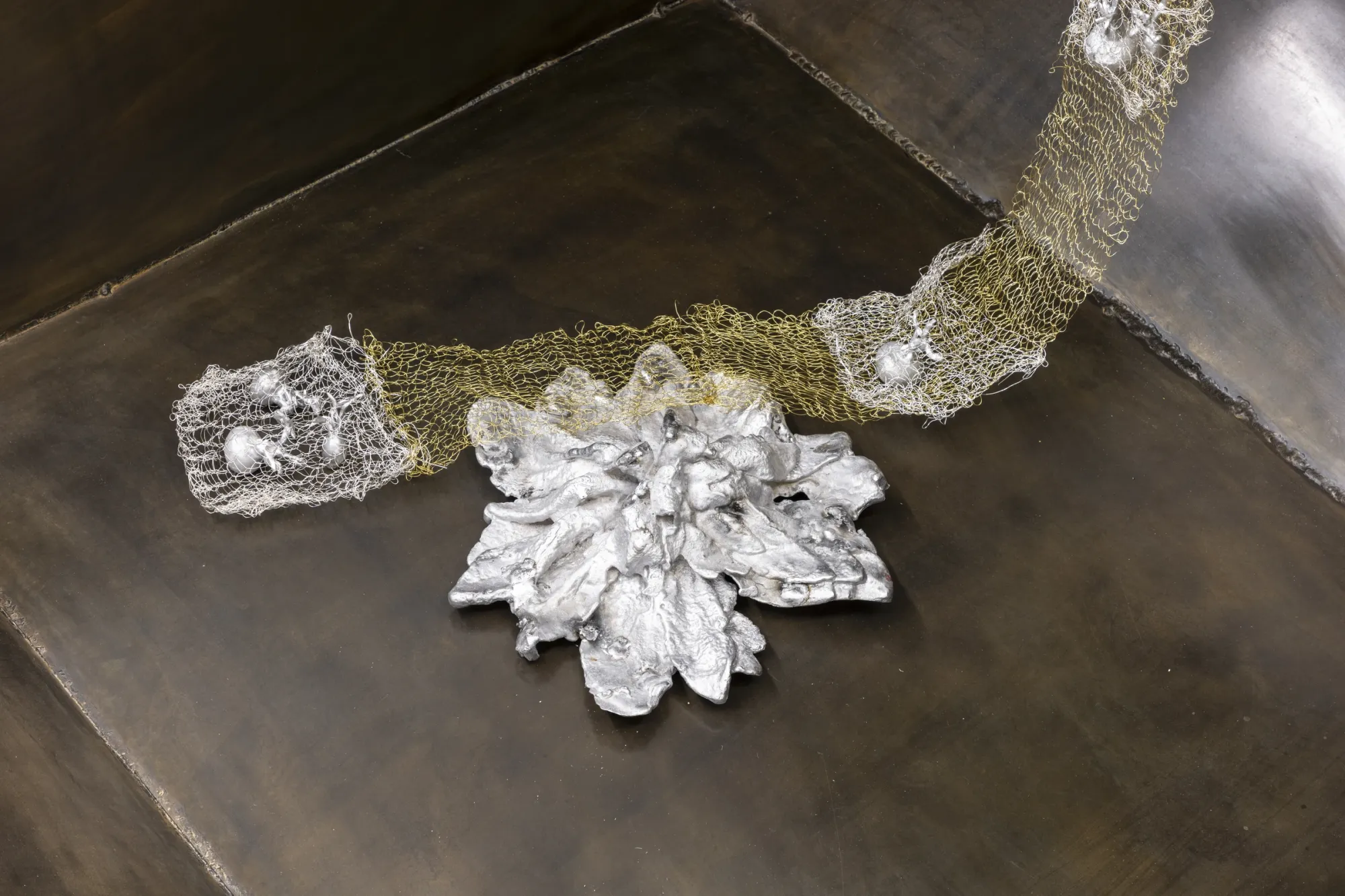 Maija Fox Hard Shoulders detail showing cast aluminium plant form connected by woven metal wire across dark steel surface