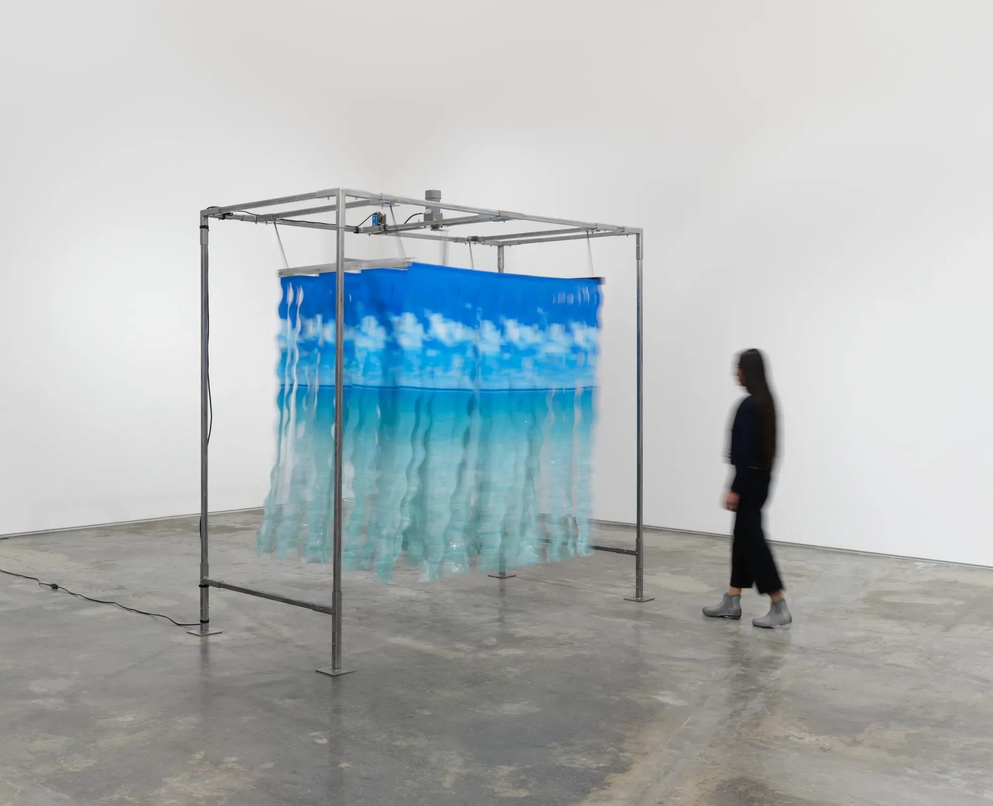 Rachel Youn , installation view -CLEANSE (I’ll do it myself) art work, reimagines a decommissioned car wash: wavy nylon strips hang from a tall steel frame, animated by an AC motor