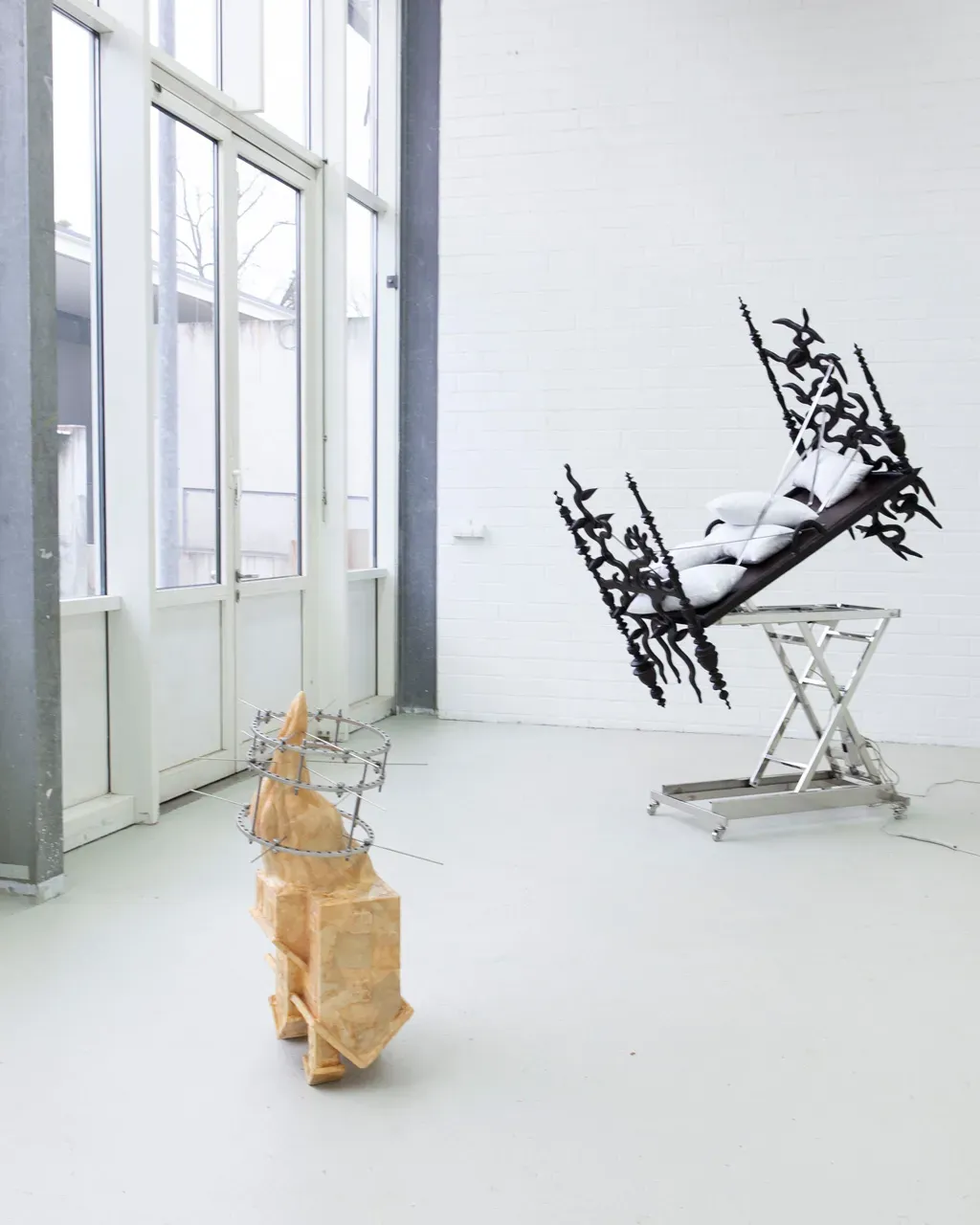 Vivienne Sun Liminality installation view with reclining medical chair covered in black organic forms and sculptural object in foreground