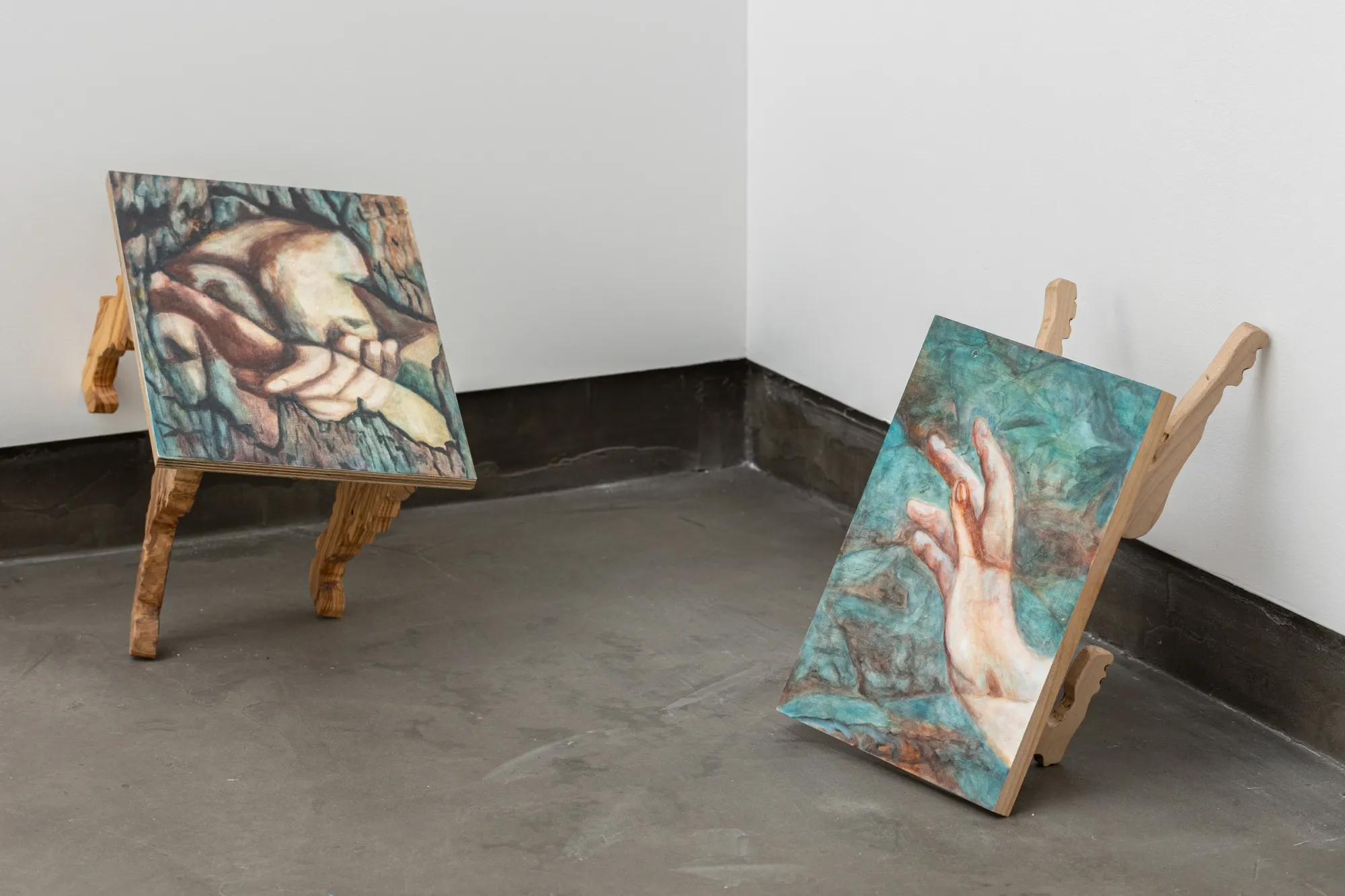 emma kling artist, exhibition view Gallery Rechnitzer, Budapest, 2026, small paintings mounted on carved wooden supports placed on the floor, showing hands and intertwined figures.