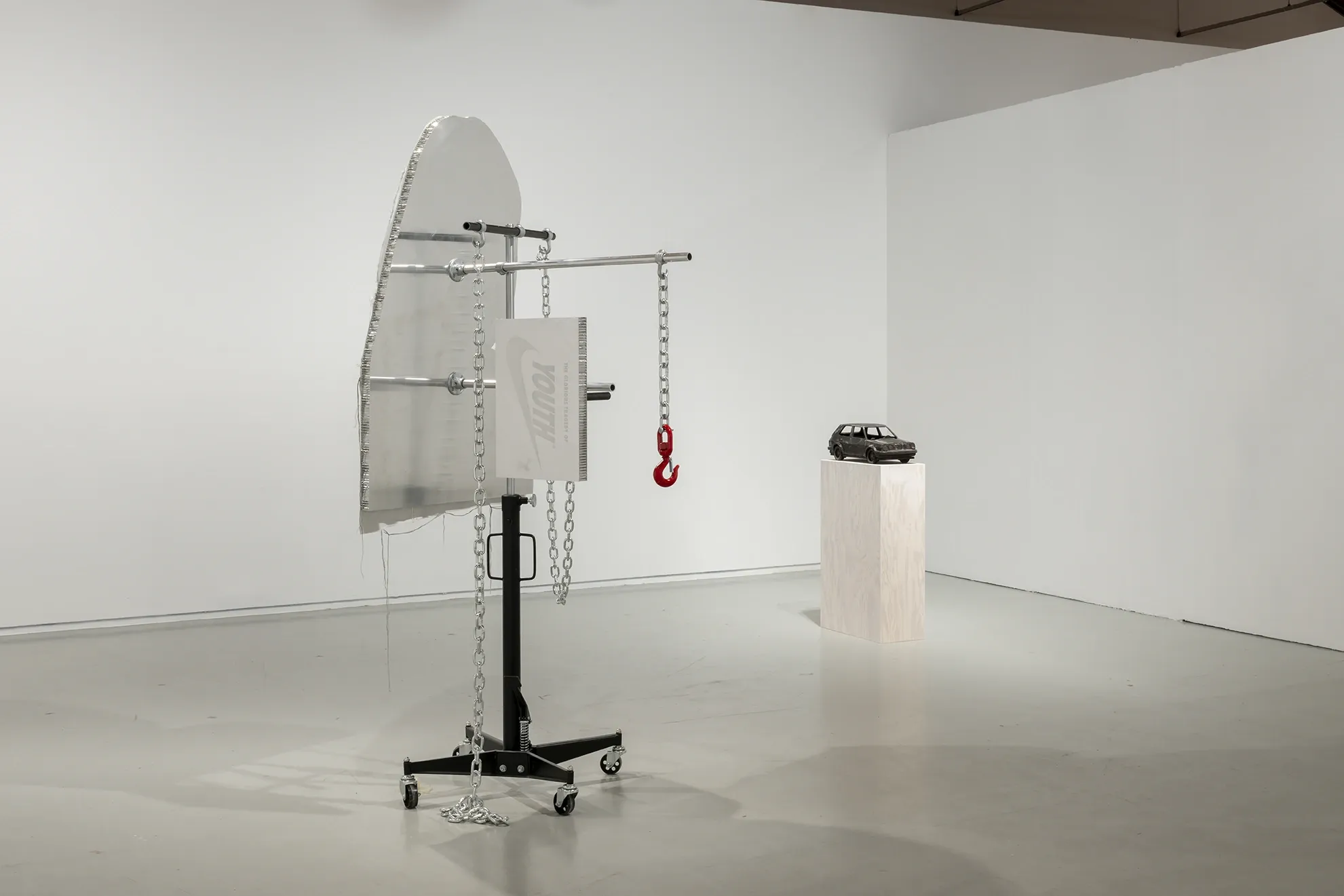 Joan Pallé, Els joves infeliços / Unhappy Youth, detail: two sculptures on wooden plinths — left, a classical-style plaster bust in robes touching its face; right, a seated figure in a white sweatshirt with head replaced by orange flames, Centre d'Art La Panera, Lleida, 2026