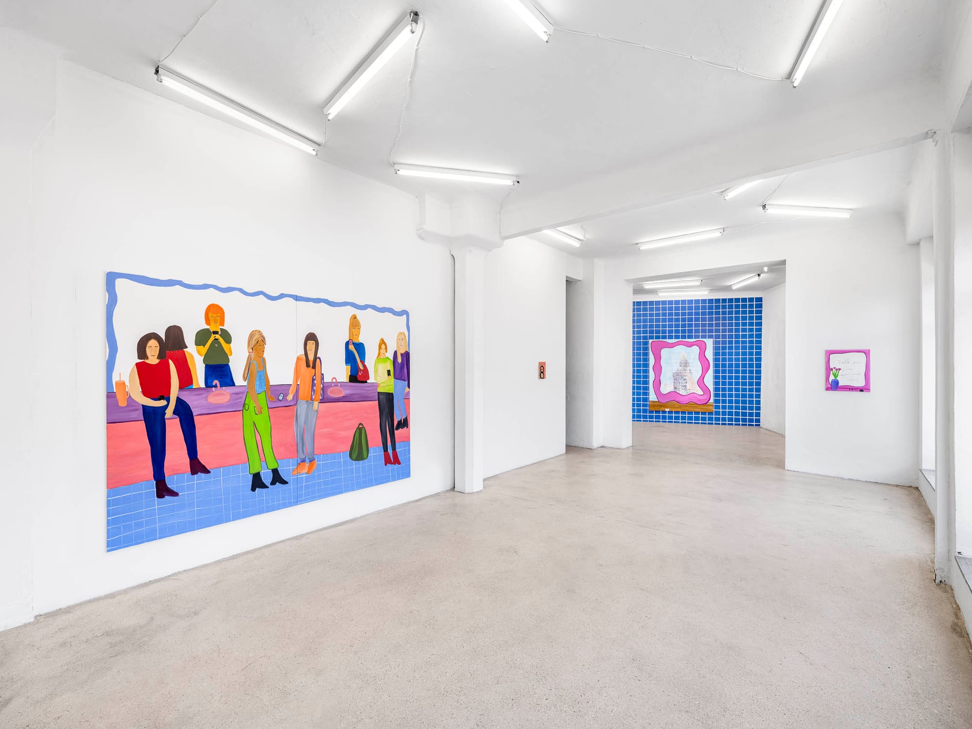 Josefine Schulz: Makeover (fall in love again and again), Kunstraum Ortloff, Leipzig, 2026 — left wall: monumental canvas with wavy blue frame depicting women at public restroom counter; through doorway: blue tile-grid room with pink-framed painting and small text painting with tulip vase visible in background.