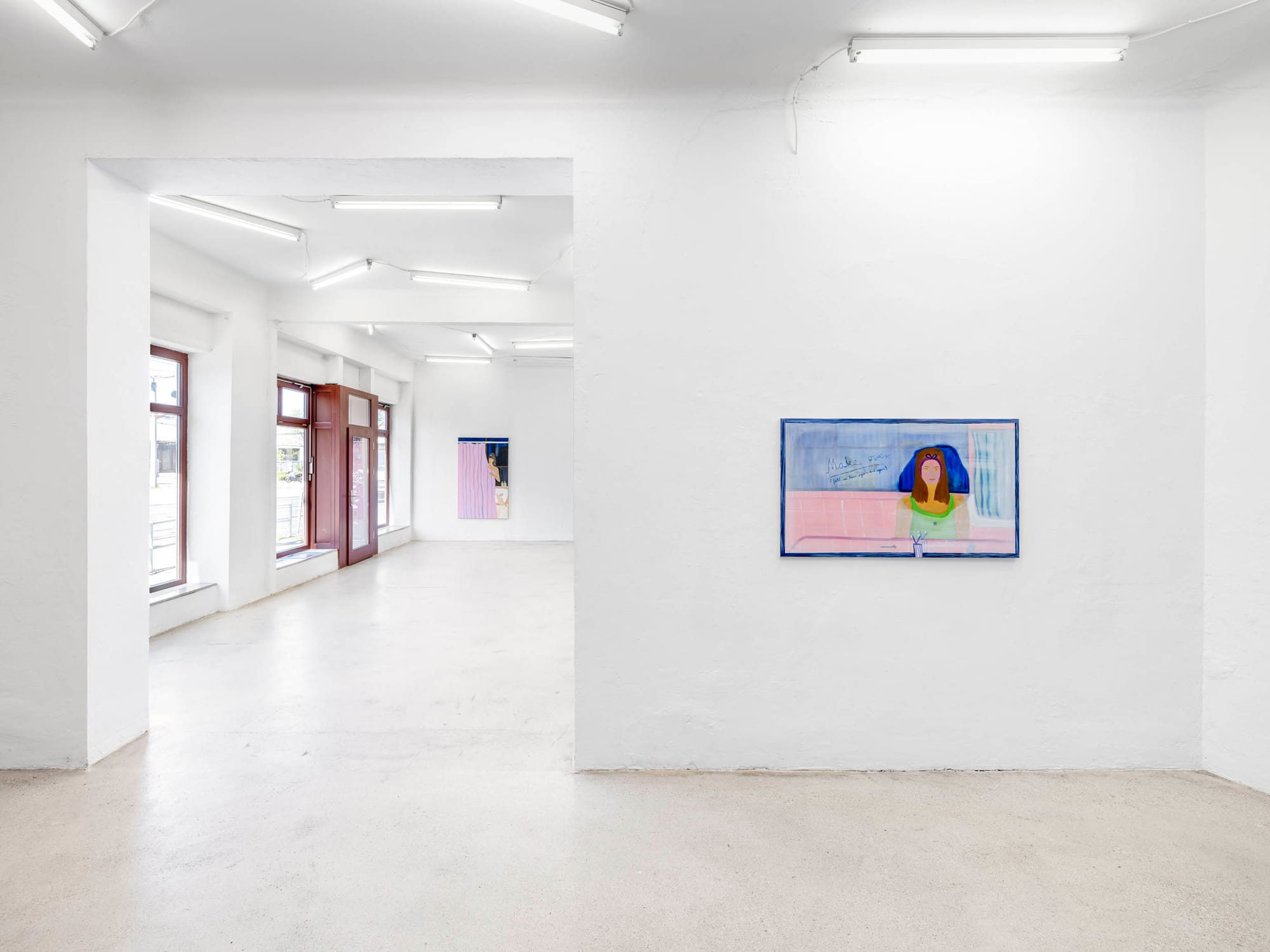 Josefine Schulz: Makeover (fall in love again and again), Kunstraum Ortloff, Leipzig, 2026 — wide Altbau hall with large windows; foreground right wall: horizontal painting with blue frame depicting woman's portrait with dark blue hair, soft pink ground, handwritten text at top; far background: shower curtain painting.
