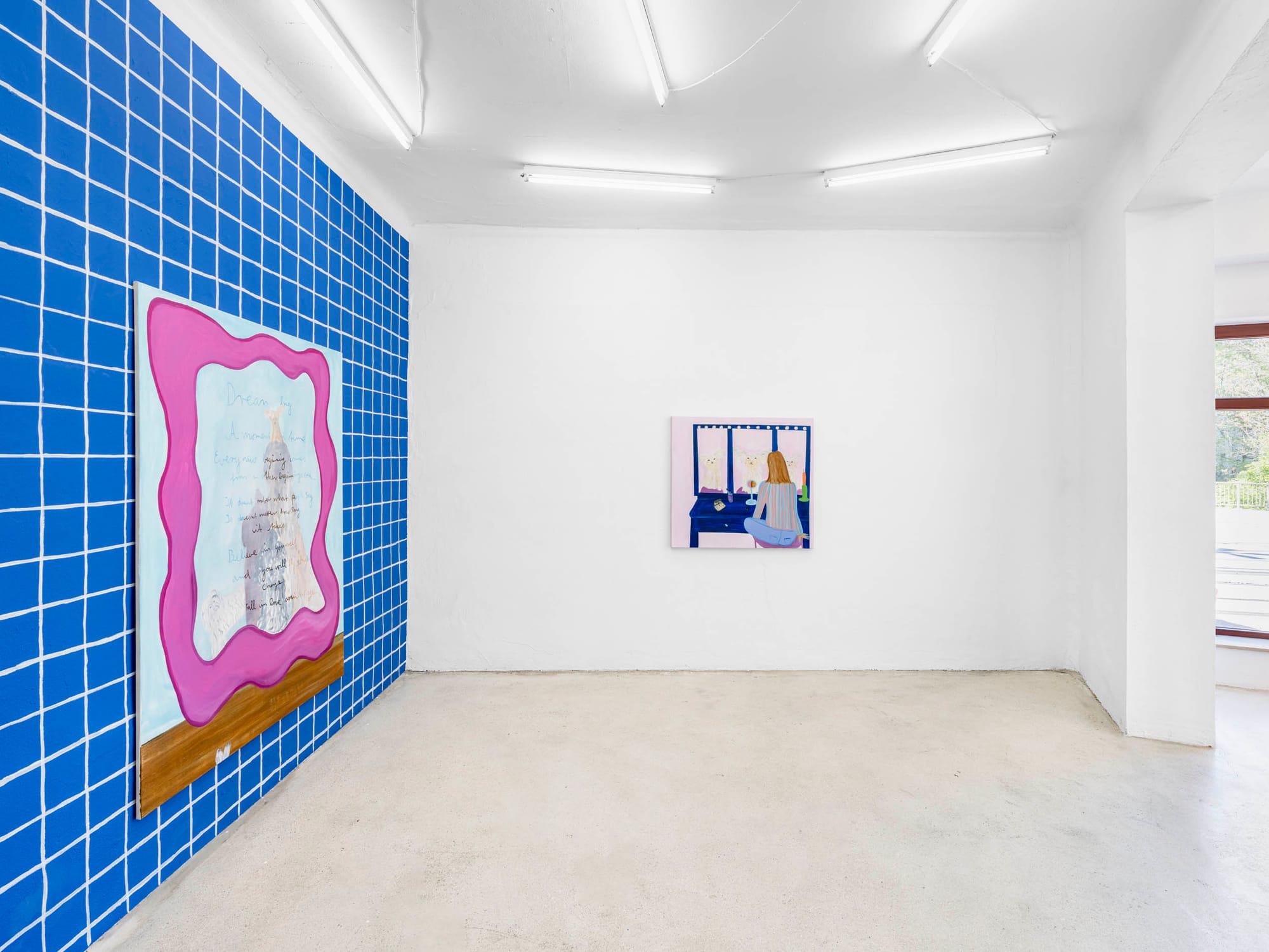 Installation view, Josefine Schulz: Makeover (fall in love again and again), Kunstraum Ortloff, Leipzig, 2026 — left: blue tile-grid wall with large pink-magenta wavy-framed canvas, handwritten text and layered architectural motif visible inside frame, wooden shelf below; right wall: painting of figure seen from behind at blue vanity mirror with bulb lights, striped top, pink ground, wine glass.