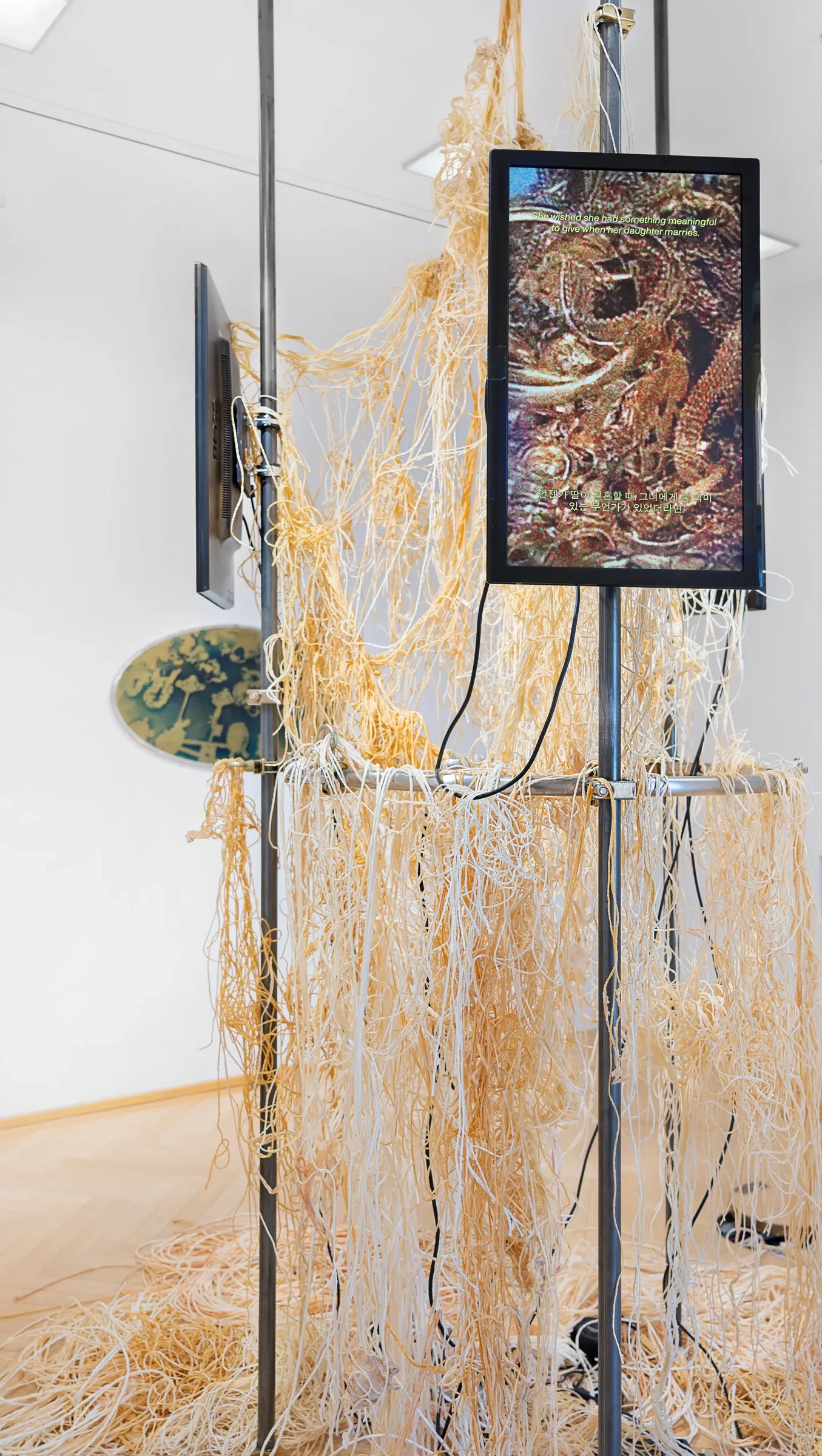 Kaja Clara Joo, 다시 : DASI, 2026, detail. Video monitor showing gold ornamental imagery, latex tubing installation, oval cyanotype work visible in background.Korean Culture Center Vienna.