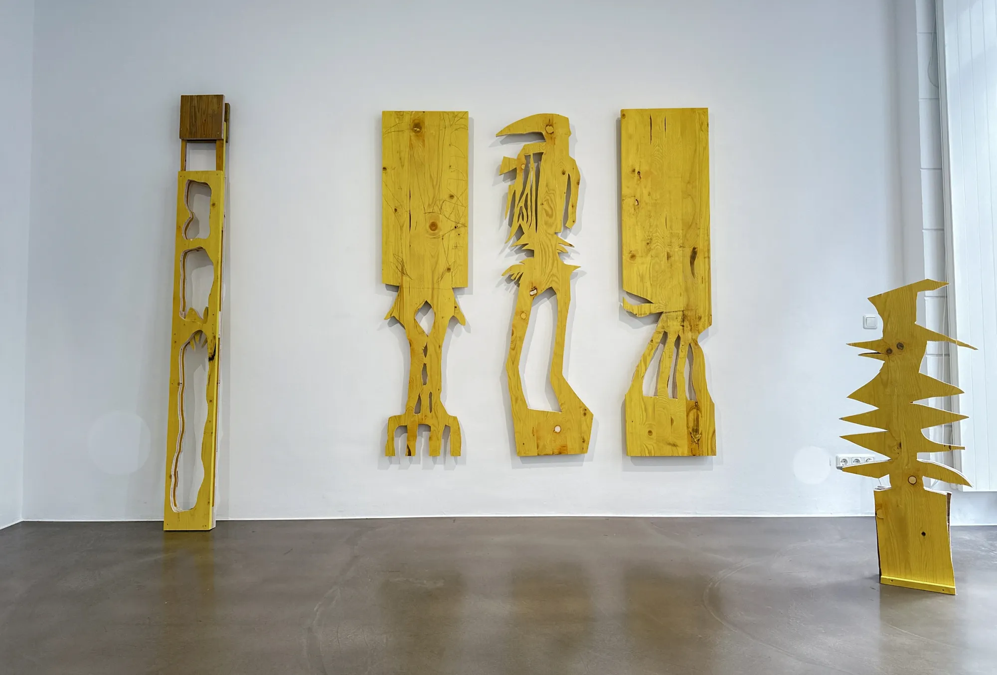 Ernst Koslitsch, three large wall-mounted yellow formwork timber panels with cut figural silhouettes, Cosmic Trigger – Respawn, Bildraum 07, Vienna, 2026
