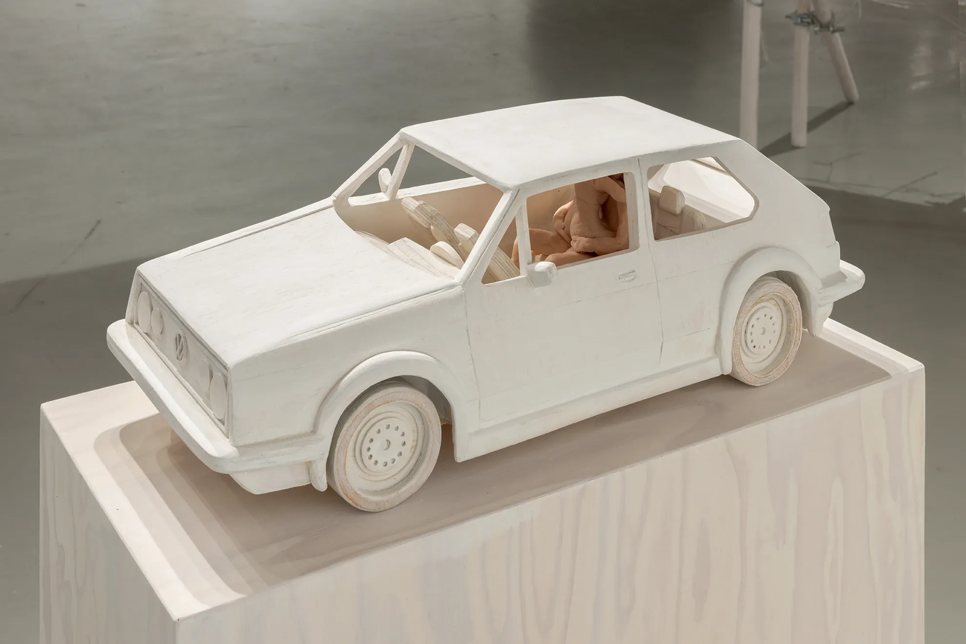 Joan Pallé, Els joves infeliços / Unhappy Youth, detail: white-painted wooden sculpture of a VW Golf GTI on a wooden plinth, with a small crouching human figure visible inside, Centre d'Art La Panera, Lleida, 2026.