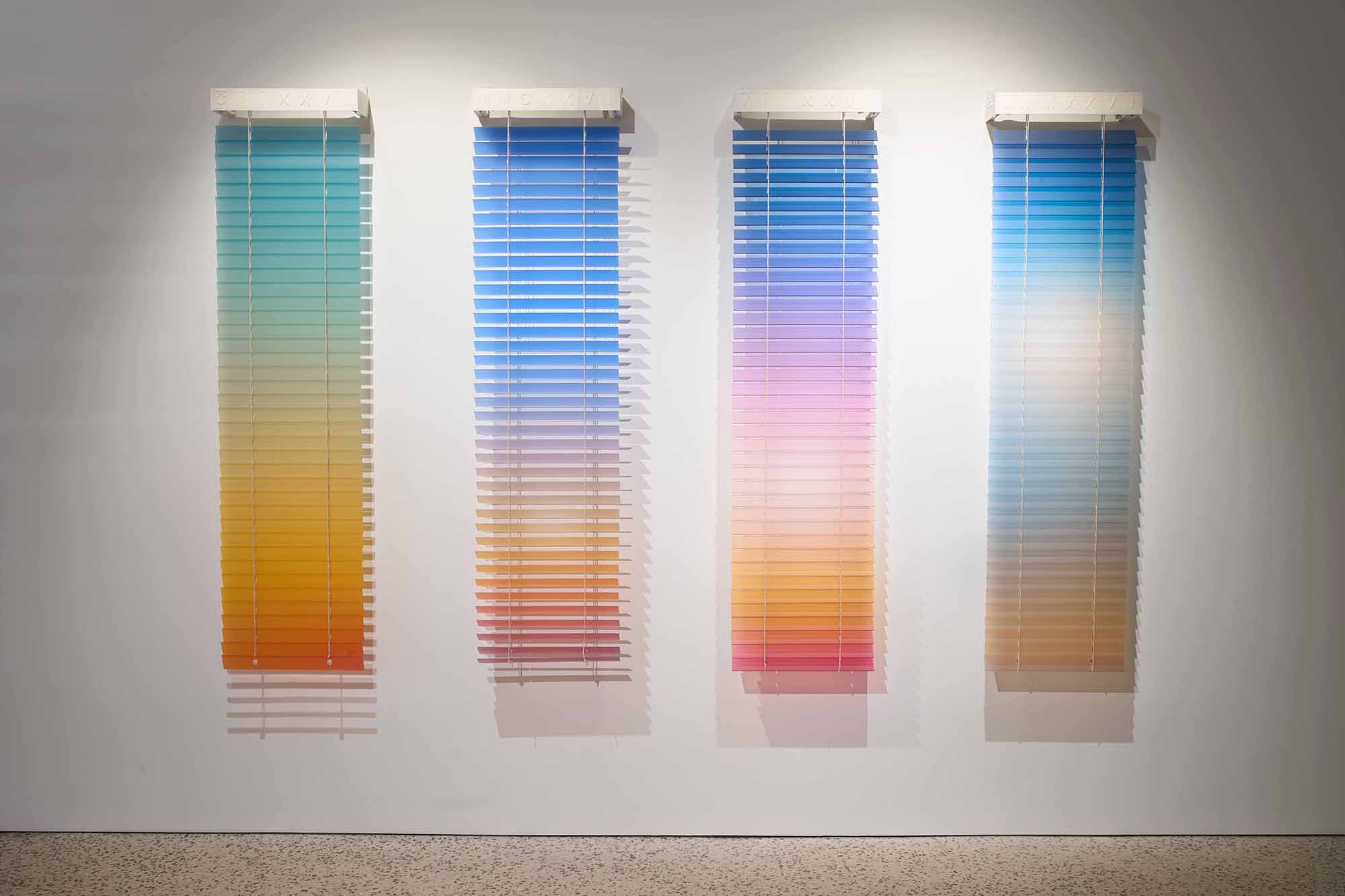 Thordis Erla Zoega, Forecast, installation view: four vertical venetian blind works mounted side by side on white wall — each carrying a distinct AI-generated sky gradient: teal-green to amber, bright blue to orange-red, blue-violet to peach, pale blue to soft white; Roman numerals visible on each valance, BERG Contemporary, Reykjavík