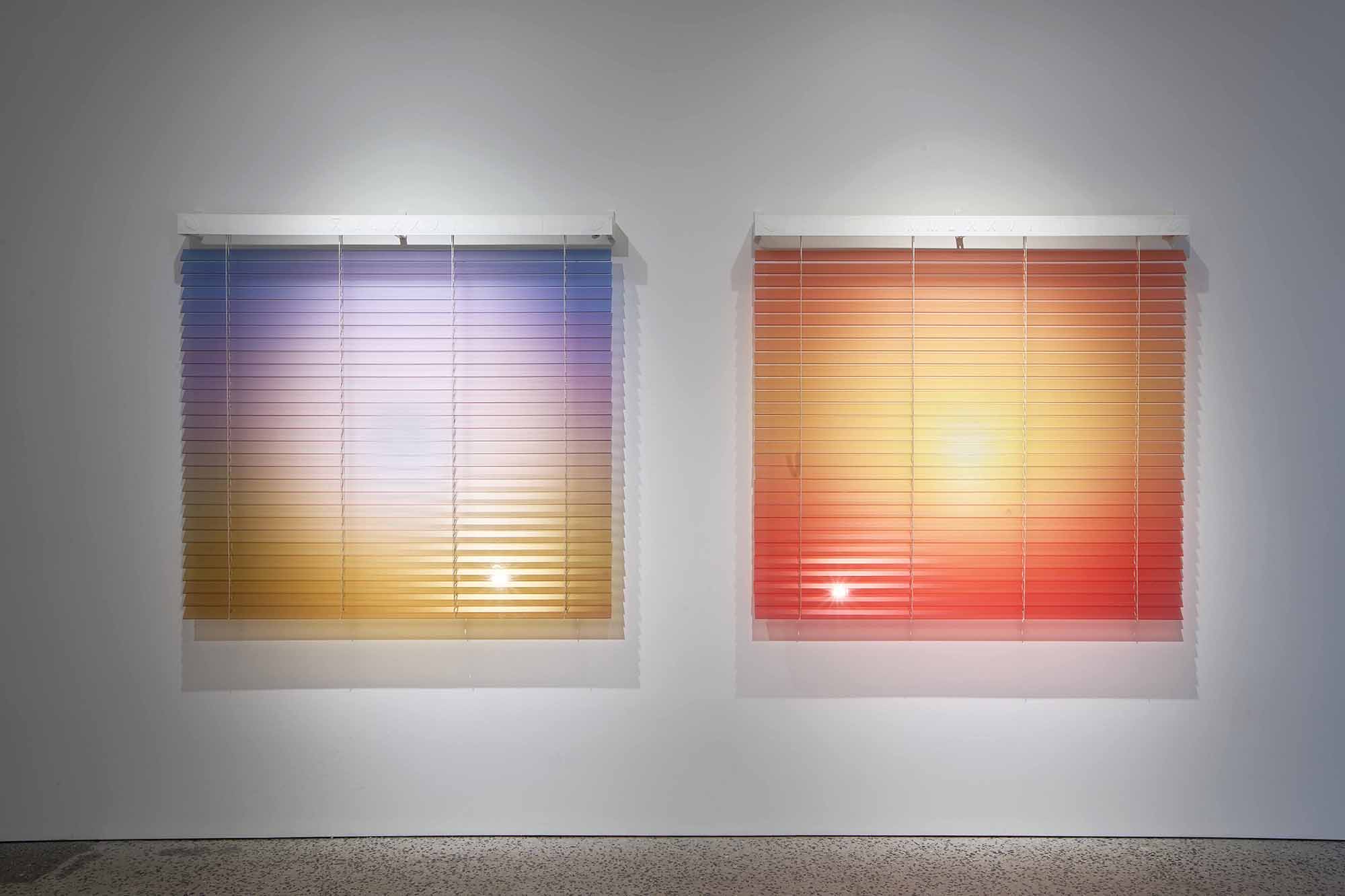 Thordis Erla Zoega, Forecast, installation view: two square-format venetian blind works side by side — left work with blue-violet gradient fading to warm gold, small luminous sun point at lower centre; right work in deep red-coral with central glowing sun point, BERG Contemporary, Reykjavík