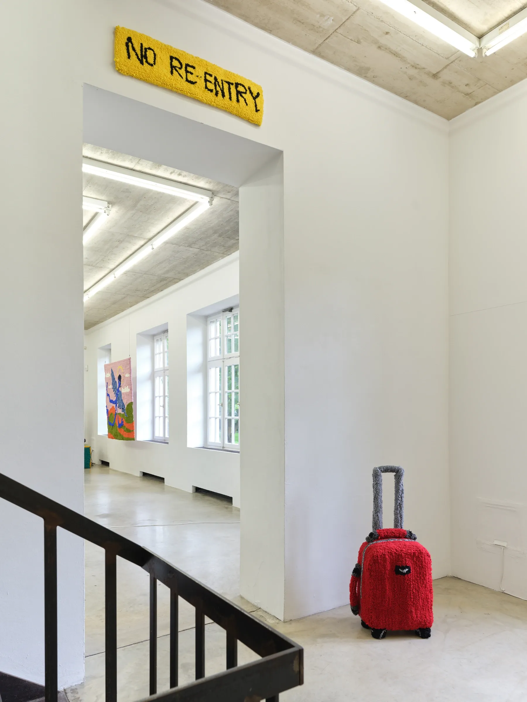 Elen Braga, Ich bin wie du, NAK Neuer Aachener Kunstverein, Aachen, 2026, suitcase under No Re-Entry sign alongside textile work