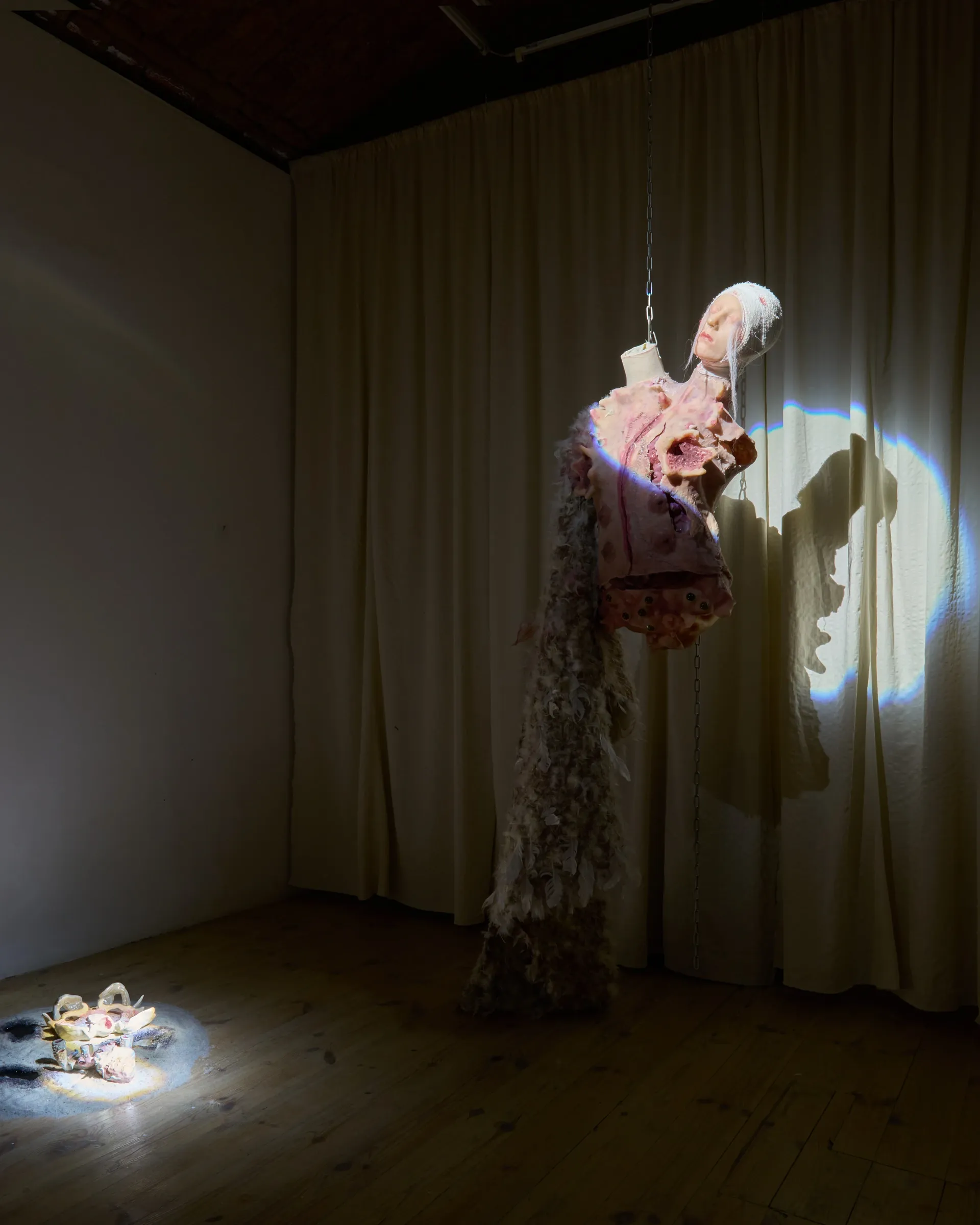 Anna Engelhardt and Tina Bxtq, Bleed Through, Galerie 35M2, Prague, 2026, room view with Postangelic costume suspended and ceramic objects on floor