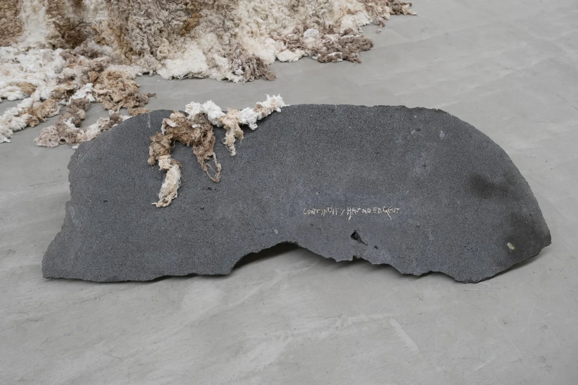 Kieffer Woodtli, AXES, Alvarez Chida, Mexico City, 2026, volcanic stone slab close-up with textile fiber and handwritten text